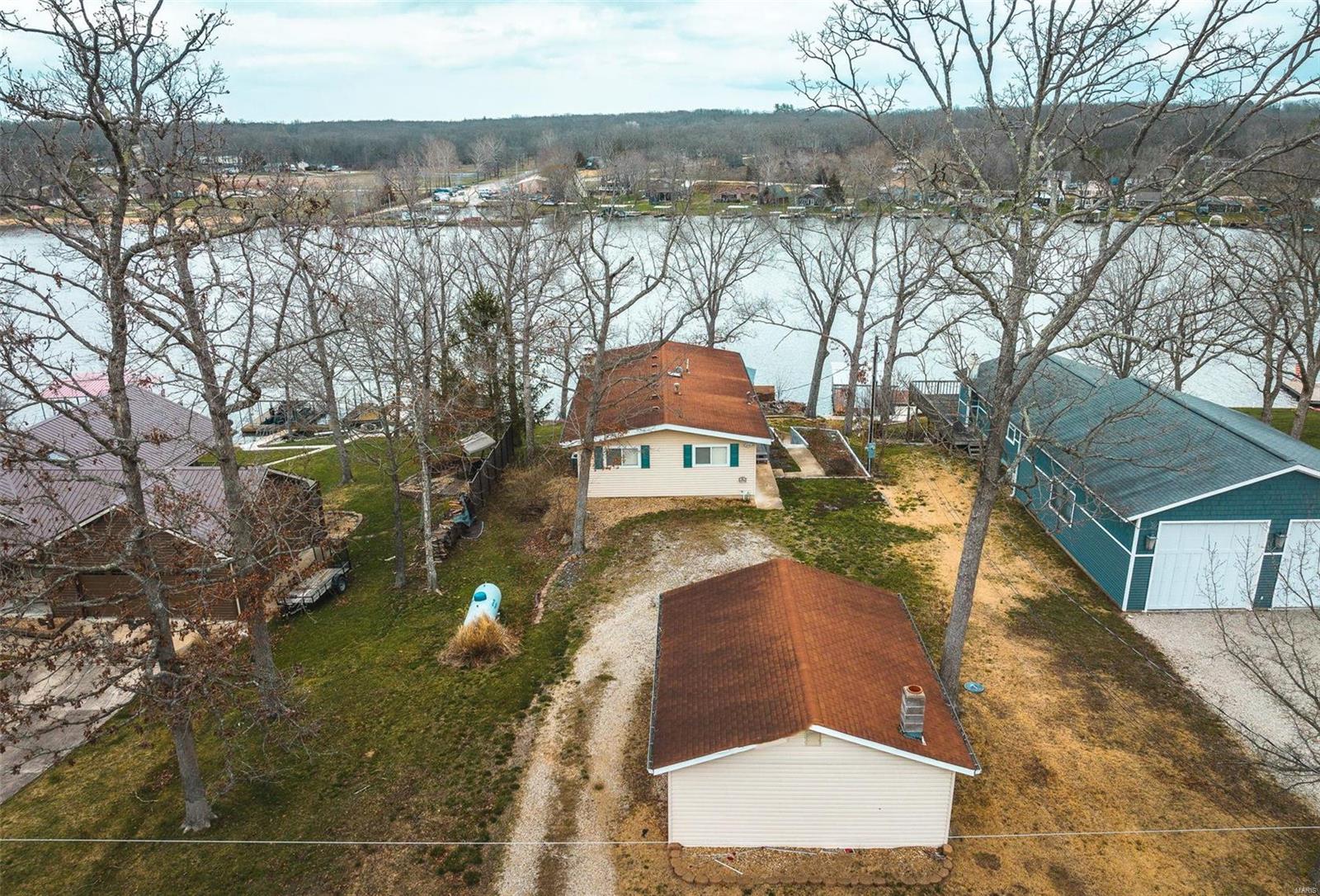 This house has everything you need to start enjoying lake life! The furniture is included. A covered boat dock and lift make boating easy! When you enter the house, you are greeted by a beautiful lake view. Sliding doors take you to a covered deck so you can sit and relax with some coffee while enjoying the sunrise! The main level has kitchen/dining/living area with a fireplace. There is also a full bath and 2 bedrooms. One is HUGE! The lower level has a laundry/storage area and an l-shaped living space which can easily serve as extra sleeping quarters. Also on this level is a wet bar. Sliding doors lead to a covered porch. The tiered back yard makes for easy access to your dock. Outside, the 2 car garage has plenty of room for your water toys and to store your boat in the off-season. Indian Lake is a gated community with a 326 (+/-) acre lake for fishing, swimming, boating, waterskiing and tubing. A full service marina makes lake life easy! ilpoa.org for association rules and bylaws.