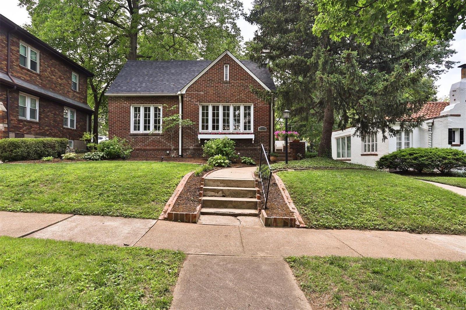 Picturesque brick cottage on central, tree-lined U City block! NEW ROOF May 2021! This 2 bed/1.5 bath ranch is the perfect hideaway, offering the charm of a cozy 1920s cottage with incredible convenience...walkable to downtown Clayton, the Loop, and North & South/Delmar. This home boasts incredible natural light via the front wall of windows. The side entry leads to open floor plan living / dining rooms w/ original hardwood floors (refinished 2018), gas fireplace, & arched doorways. The master bedroom has been expanded to include the former sunroom, & offers an abundance of space to work, exercise, or relax. The second bedroom is also spacious and could easily be the primary bedroom. Updated bathroom on is on the main floor, & there is a half bath in the basement. Kitchen is classic and cherry with black & white tile, pantry and sweet breakfast bar. The yard is an oasis, fully fenced with two private patios,  mature landscaping and 2 car detached garage. This darling house won't last!