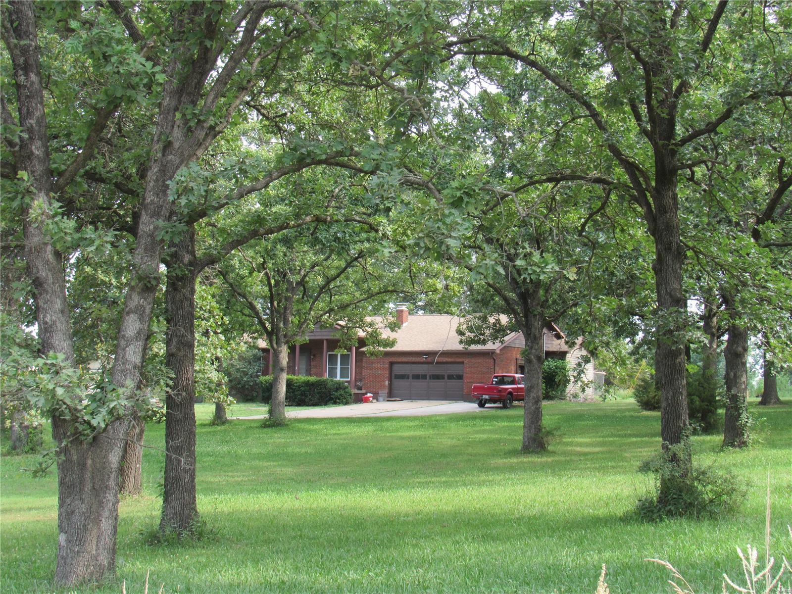 This home is a diamond in the rough. Brick 3 bedroom home nestled on 18.7 acres with a stocked lake and beautiful peaceful setting. Large park-like front yard and treelined property. There is a 30x60 building used as a shop with electric and lean-to-storage bays on each side. The trailer is used for storage can stay or could be removed. I cant wait to see what you do with this home with a simple update. There are some wood floors and shag carpeting, what a surprise it would be to pull the carpet and find beautiful flooring hidden underneath. Newly installed Classic wood boiler to heat the home and water!  Enjoy your morning coffee on the large screened-in porch overlooking the lake. Plenty of room for horses, a mini-farm, gardens and so much more! Come make it yours before someone else does!