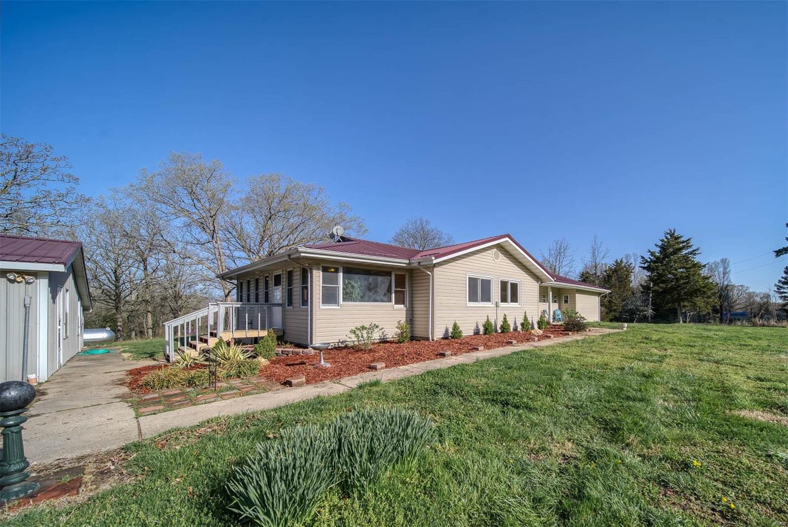 This is a great house just out of town on over 6 ACRES w/ a small pond and a great SHOP! The pine tree surrounded entry is just the beginning of this little oasis near Rolla, MO! Enjoy over 2,000 sq ft of living space to include 4 bedrooms, formal dining room, laundry room, huge sunroom, living room and large eat-in kitchen. The sunroom is the first room from the garage and can be utilized as a large family room w/ with stairs down to the small unfinished basement. The kitchen is next and it is BIG, with a center island and a breakfast bar that looks into the living room with woodburning fireplace and wood flooring. There's a formal dining room off of that same space. The shop measures 35x23 and also has a lean-to on the side and a space once used as an office with it's own entry. Clear a few trees and the view could be even better. Call to see this one today! Additional Rooms: Sun Room