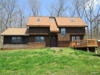 Rustic Country Home surrounded by 15 acres--mostly wooded-When -has a quiet/private setting to call your own! This 1.5 story home has 3 large bedrooms and 2.5 baths and rustic charm throughout--from the wood beams in the living room, freestanding woodstove, country kitchen, to the wood flooring in upstairs bedrooms.  Main floor master with master bath and walk-in closet.  Freshly painted throughout, and some new carpet too.  Just outside the kitchen French doors, relax on the deck and enjoy the peaceful outdoors. The 24X30 outbuilding with electric and concrete floor makes a great workshop/garage.   Woods provide abundant wildlife for hunting. Main floor is partial earth contact home.  Come see today!