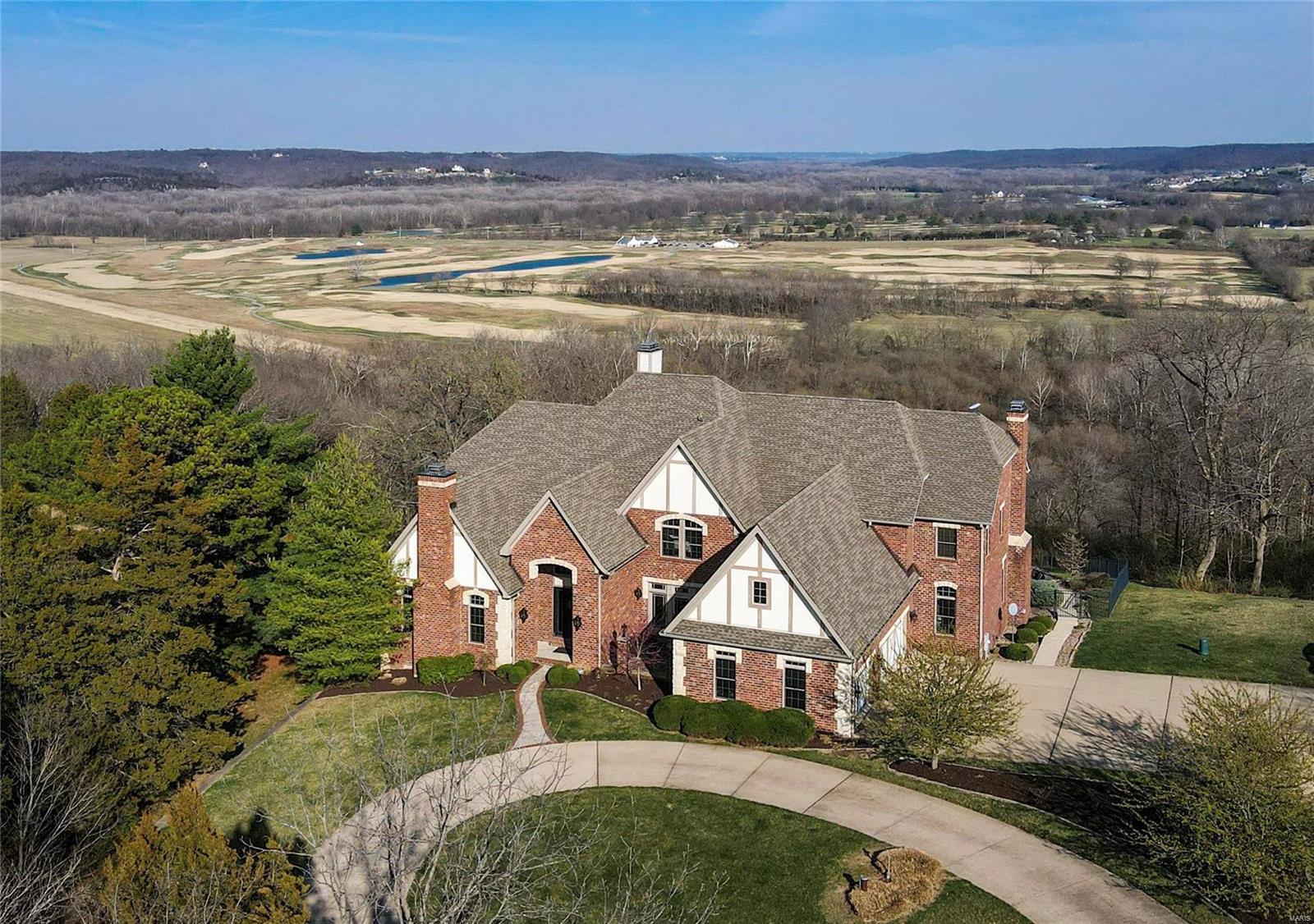Nestled on a 3 acre estate, overlooking the Meramec River & 3 golf courses, this stately 1.5 sty home offers an incredible oasis! The resort style infinity pool w/spillover spa & separate hot tub allow you to enjoy the serene views while entertaining in style. Grand 2 sty foyer welcomes you, flanked by a den & dining room w/private patio. Beautifully appointed, the great room hosts soaring ceilings, custom built-ins & breathtaking views. The wet bar opens to the gourmet kitchen hosting top of the line appliances, custom hand painted cabinetry w/intricate moldings, granite counters, butler's pantry & adjacent hearth room w/stone fireplace. Offering a lavish retreat, the primary suite provides private access to the covered deck, dual walk-in closets & vanities, soaking tub & separate shower. A bonus room, 3 guest bedrooms, & 2 full baths grace the upstairs. The lower level is an entertainer's dream w/an extensive bar, stone archway leading to the wine room, guest suite & rec room! Additional Rooms: Wine Cellar