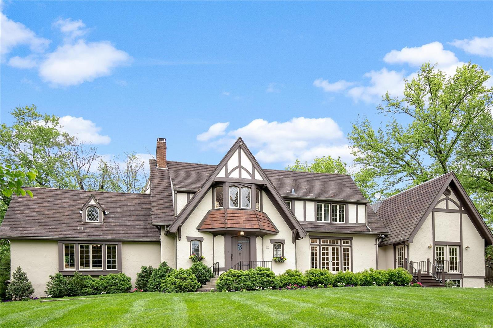 GREAT PRICE REDUCTION!  Exuding charm, this 4 bedrm, 3.5 bath tudor home is perfect for family and entertaining your friends from the neighborhood.  Situated on a private 1.5 plus serene acres with pool, this home opens at every turn with beautiful French doors leading out to gorgeous patios from your formal dining rm, family room and main floor master suite.  The kitchen with stainless appliances, custom cabinetry and stone counters is the heart of the home opening to the breakfast room and the family room with wet bar.  A laundry/mudroom and guest powder rm complete the first floor.  A bedroom suite with walk in closet and 2 other bedroom with hall bath are found on the second floor.  The 3rd floor is a perfect rec room.  The unfinished lower level has a high pour under the Master addition that can be finished to your specifications.  Such a beautiful setting in the heart of Ladue, walkable to Ladue schools and shops.
