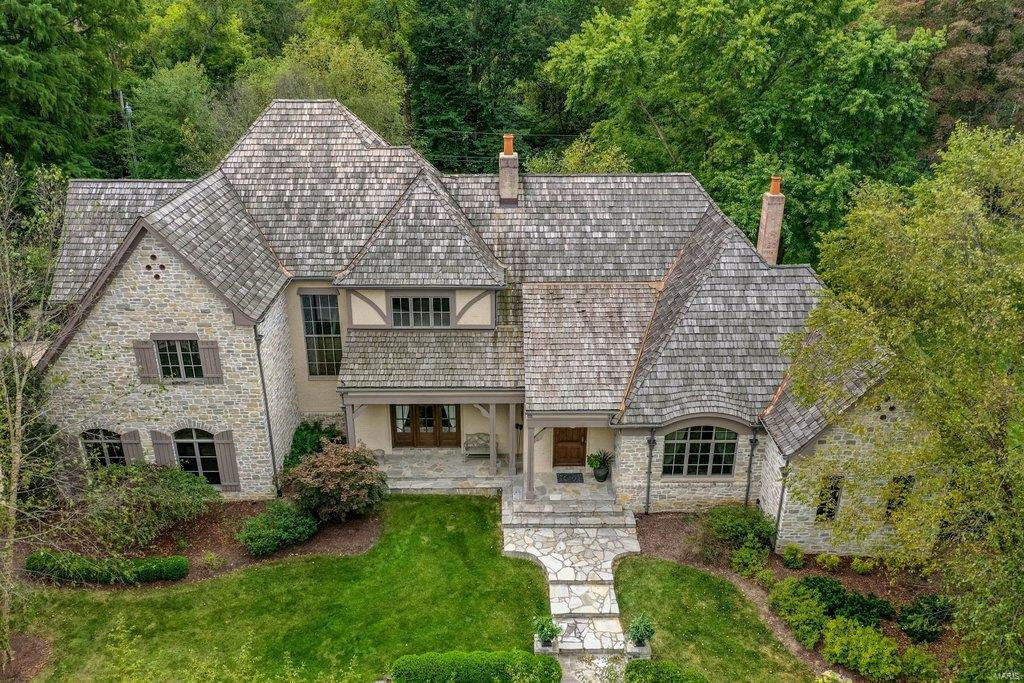 Situated on a beautiful 1.29 Acre Lot, this Extraordinary French Estate home redefines luxury living. Impressive foyer leads to elegant dining room, handsome study w/ maple bookshelves & stunning great room w/ rustic beamed ceilings, cast stone fireplace, wine cellar & French doors that open to expansive veranda. Designer kitchen with 42” custom cabinetry, granite countertops & commercial grade appliances adjoins breakfast room & hearth room highlighted by Tuscan styled fireplace. Coffered primary bedroom suite, luxury marble bath w/ freestanding tub & shower spa offers an appealing retreat. A second ensuite bedroom completes the main floor living space. The 2nd floor extends the living quarters w/ 3 bedrooms, Jack & Jill bathroom &. generously sized bonus room. Lower Level includes recreation room w/ gathering bar, fitness studio, 1/2 bath, sleeping area, office & full bath. Exterior features 4 car garage, resort style pool & hot tub surrounded by landscaped gardens & pergola