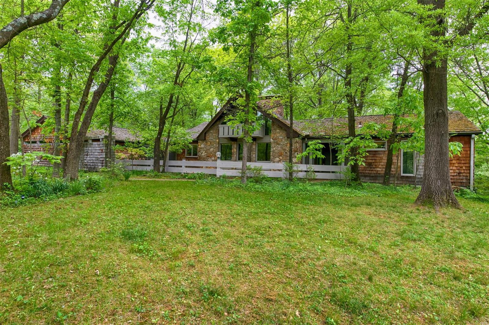 Good design is timeless. Designed in collaboration with Ralph Fournier is this impeccable mid-century home. Located on a private wooded acre. You will love the living room with vaulted ceiling, stone fireplace and a wall of windows and sliding doors that lead to a deck overlooking the lush backyard. The dining room is perfect for entertaining with view of the courtyard. There is a fun loft space that is ideal for an office or play area. The main floor master bedroom is spacious with sliding doors that open to a balcony & another set that leads to a screened porch. The master bath is gorgeous with an onyx-topped vanity. Two other bedrooms are on the other side of the home. The hallmark of the home is a captivating atrium with indoor garden & spiral staircase that leads to the family room with fireplace & walkout to the back patio. The lower level also features a 4th bedroom, full bath, cedar closet & large storage area. 3-car garage. Main floor laundry. Close to popular Longview Park.