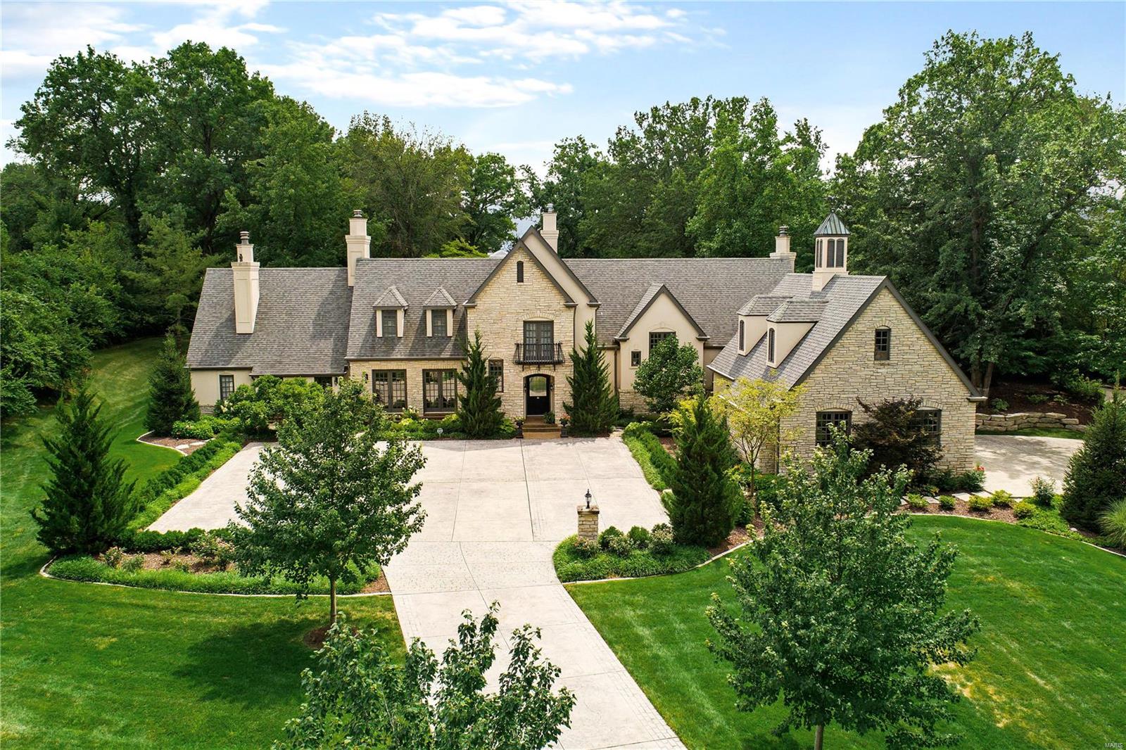 Handsome stone Manor style home w beautiful English detailing. French door from every first floor room let in light & provide easy access to the outdoor living spaces. Timeless design & fresh inspiration welcome you upon entering this classic Ladue home located on a secluded & peaceful 2 acre lot. Creatively designed offering 5 bedrooms, 6 full & 2 half baths. Luxurious vaulted main floor master suite opens to private patio. Four additional ensuite bedrooms upstairs. Charming living room adjoins gracious dining room. The kitchen, worthy of a chef, complete w top of the line appointments, includes spacious breakfast/hearth room & is accented by soaring vaulted ceilings and rich stone fireplace. Finished lower level boasts full bar, family room, rec area & full bath. Extensive landscape & driveway renovation by Poynter Landscape & Construction. Fresh, open bright and immensely livable while crisply appointed & impeccably maintained. Prime Ladue Street in enviable location!