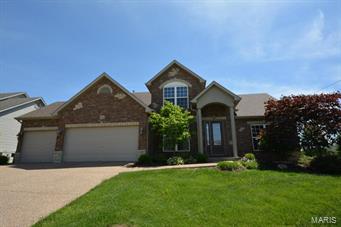 WELCOME HOME! Stunning 4BR 2.5BTH 1.5sty that shows like a display! A picturesque setting w/massive curb appeal offers brick/vinyl front, covered porch w/stately columns, lush landscaping w/irrigation system, 3 car garage & an IN GROUND POOL! Walking in the grand entry foyer w/gleaming HW floors, you'll see the elegant dining rm. The vast great rm has tall ceilings & gas FP flanked by windows. You’ll love the kitchen w/custom cabinets, tile backsplash, breakfast bar, stylish black appliances, pantry & breakfast rm. Enjoy the hearth rm w/a WB fireplace & door to the fenced backyard featuring an in ground pool w/patio perfect for outdoor entertaining & enjoyment. MF master suite offers a walk-in closet & deluxe BTH w/dual sink vanity, soaking tub & sept shower. Upper lvl has 3 add'l BR, full BTH & den.The partially finished LL w/rough-in for BTH offers a family rm & rec rm bringing your total livable space to 2660+SF.  Great location w/easy access to major hwys & Wentzville Schools!