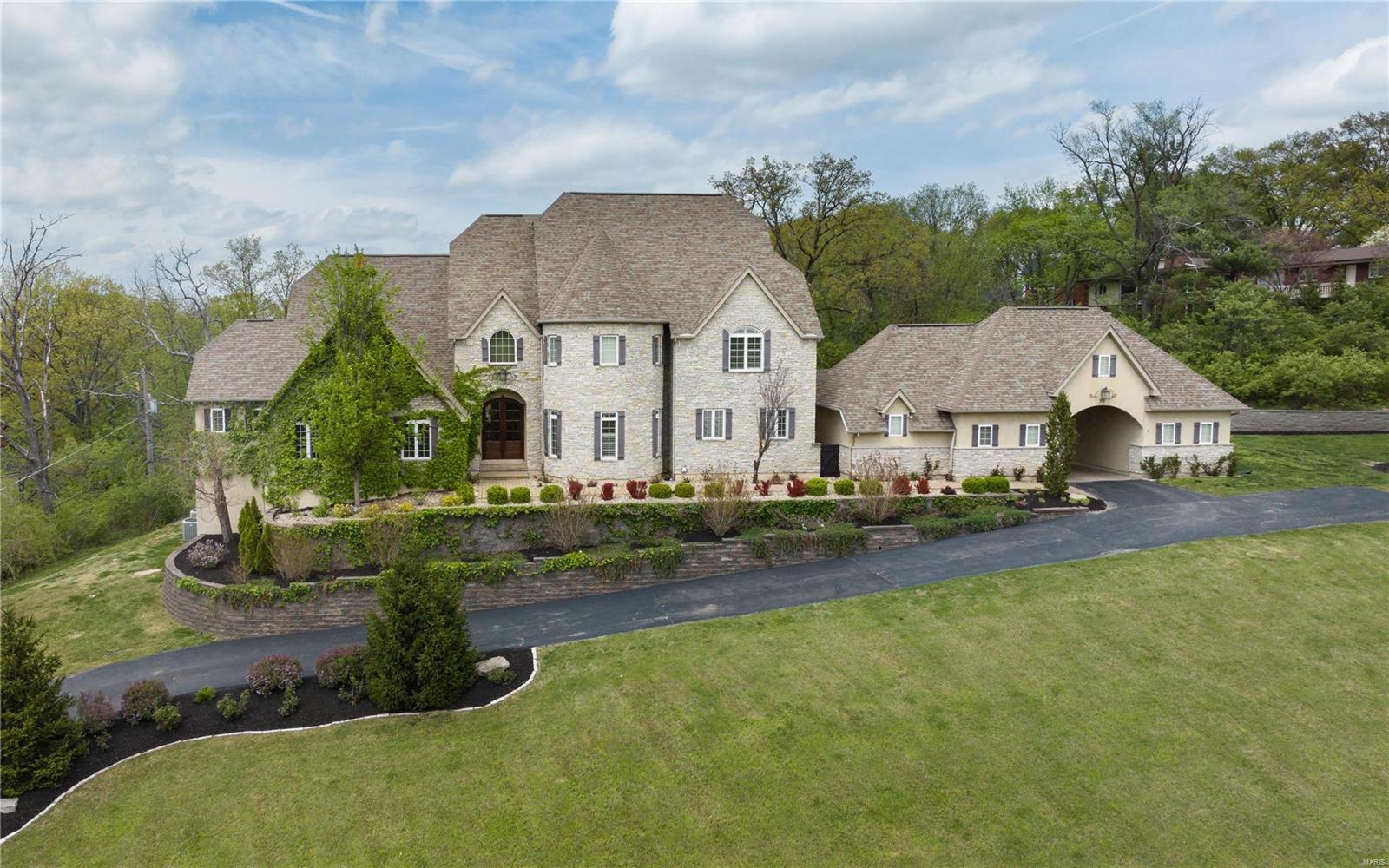 IMPROVED PRICE. This newer construction all custom Executive home was specifically chosen when built for it's site. Unique in St. Louis, it sits high atop a hillside, with panoramic, commanding view and a breathtaking approach from the street. French inspired, every amenity is available in an expansive 8,500 square feet of total living space. The 1.5 story retreat encompasses 5BRs. A Primary and auxiliary Suite are both found on Main Level. The main Suite has dual walk-in closets, vaulted bath, den and FP. The Great Room and Hearth Rooms overlook a resort-like like pool, patios and water features. The kitchen features high end appliances, large island, and pantry. 2nd level finds 3BRs, 2BA. The walk-out finished Lower Level is an entertainment paradise: billiards, gaming, bar, theater, wine cellar, gym, craft room and BR. Stellar outdoor space; a vaulted covered living area with FP are destined for 12 month use. Laundry and pet spa located on main. Porte-Cochere with addtl parking. Additional Rooms: Wine Cellar
