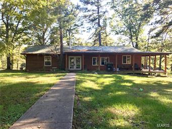 This lovely ranch home sits on 13.1 acres that includes a shared 7 acre private spring-fed lake PLUS a pond, both stocked, just 15 minutes from Rolla. (K-8 in Dent/Phelps and Rolla High) The inlet to the lake has a sandy wading area that leads to beautiful rock bluffs surrounding the shoreline. The one-level ranch has a split bed floor plan w/3 BR and 1.5 BA, wrap-around porch w/access from the master bedroom and plenty of yard. The north and west sides of the home have log siding while the rest is cedar. The great room includes the living, dining and kitchen areas in an open-concept format complete with vaulted knotty pine ceiling, black enamel wood stove with stone hearth, kitchen island, breakfast bar and all stainless steel appliances. The hickory cabinets are topped with black granite tile countertops. The detached garage has a large shop and space that could be guest quarters. A lean-to, chicken hutch and 3-sided shelter complete this little piece of paradise. Don't miss this! Suitable for Bed/Brk