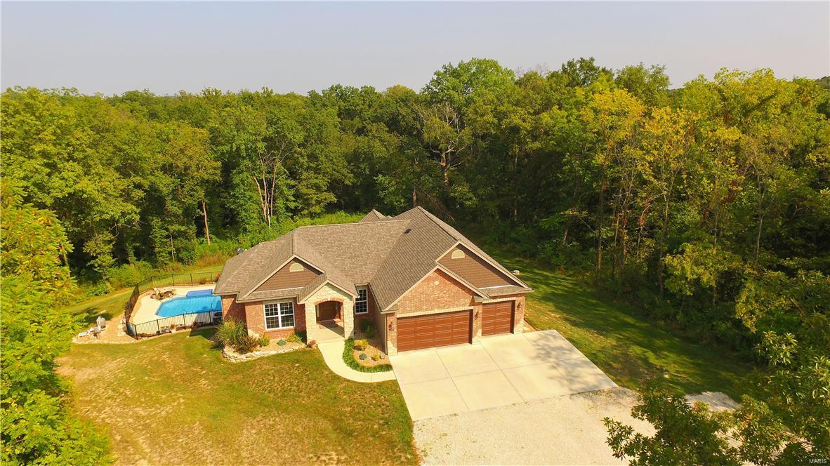 Stunning custom built ranch on nearly 4 acres of perfection! Your dream kitchen awaits w/ granite countertops, 42 in cabinets, island with double sink, dishwasher, electric range & built in microwave w/ convection oven. Split bedroom floor plan w/ master suite off vaulted hearth room w/ coffered ceilings, recessed lighting, w/in closet &luxury bath w/ granite top vanity, jetted tub & shower. Spacious secondary bedroom w/ private full bath & w/in closet & den/office area off past the vaulted great room. Incredible walk out finished lower level w/ large family room area, additional bedroom w/ another private full bath & w/in closet, custom built bar and rec area, & additional bath w/ direct access to pool area. Enjoy the summer months in your private pool w/ fountain, covered patio, deck & fire pit area. Attached 3 car garage & detached 24x40 for all your hobbies and collections! With acceptable offer, seller is willing to either pave gravel road/driveway or credit buyer at closing.