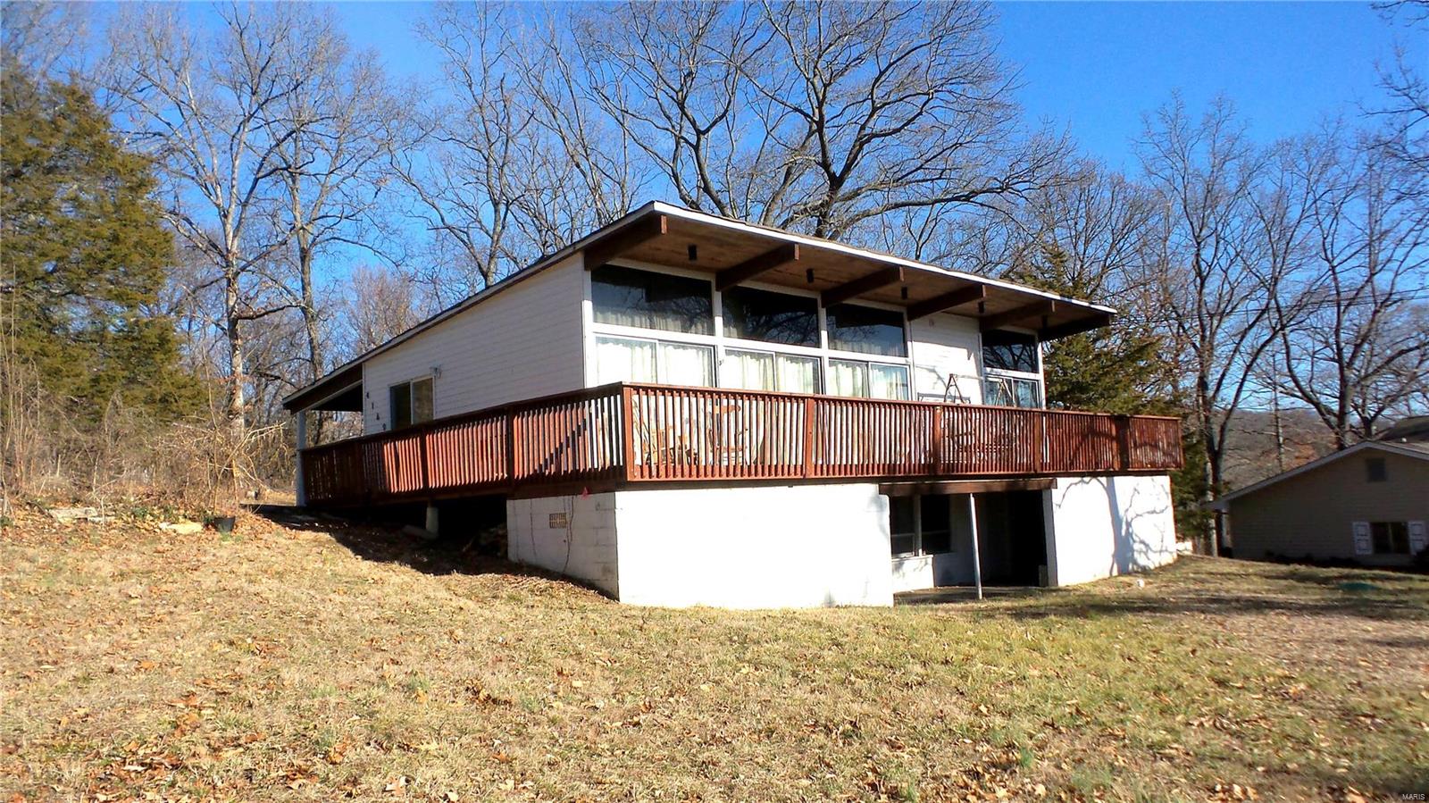 Lake living paradise. The front wall of floor to ceiling windows allows you to enjoy lake views while sitting on your couch keeping warm with the wood burning fireplace or from your private wrap around deck. Kitchen has an eat-in bar with a vaulted dining area/ living room. Coupled with beautiful wood beams throughout the ceiling, the home gives you that open concept floor plan & lots of natural lighting. The walk-out basement offers a ton of storage, laundry, workspace and can easily be built out to add some additional living space. Backs to woods & on a corner lot. A fisherman's paradise with access to a 72- acre lake and 3- acre pond.  HVAC system throughout the home. The basement has a system to support the back concrete block walls & sump pump for dryness so everything is ready for the space to be finished. The covered patio/parking area could be converted to a screen porch. Your secure in the private, gated, picturesque community of Lake Lorraine.