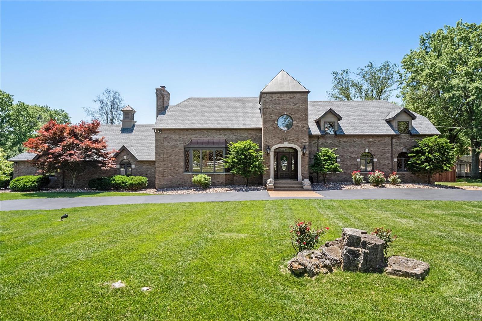 Built in 1939, timeless elements of the original 2 bedroom Sunset Hills gem still exist in solid oak paneled doors, extensive millwork, casement windows and handmade wood plantation shutters. The Family Room fireplace and carved mantel still stand in what is now the cozy den. The main floor bedroom and updated full bath is perfect for short or long term guests. In the 90s, a grand addition was made transforming the home into what it is today. Spacious primary suite with luxury bath overlooks the dramatic 2-story great room with richly paneled wall treatment, seamlessly tying the old and new together. Light-filled gourmet kitchen with large center island and stainless steel appliances opens to the formal dining room. Two covered porches overlooking the private inground pool area, with ample decking area for sunning or entertaining. 4 car attached AND 3 car detached garage each feature heating & cooling, electric, 220 outlets, and utility sinks. Both garages have space for a lift.