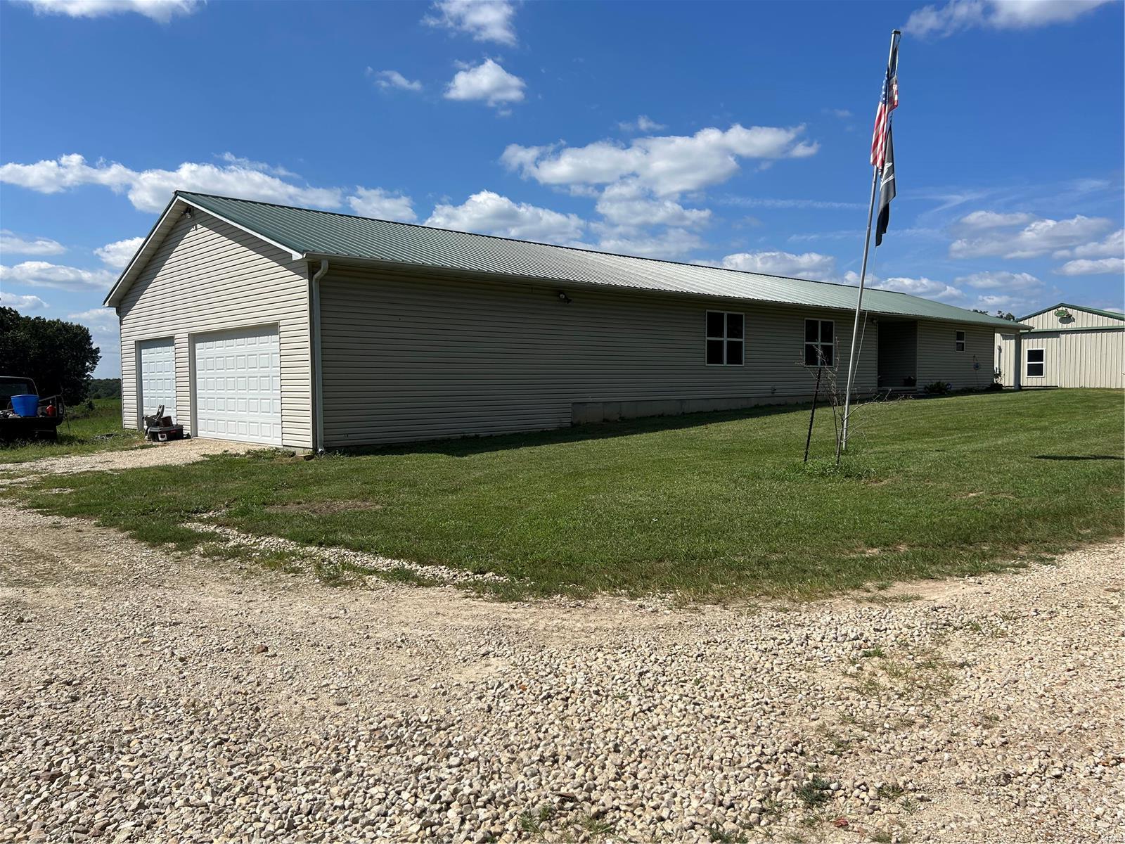 Family-Friendly Farmhouse ready to welcome you home. This move-in ready 4/2 ranch-style home overlooks 30 acres of woods and pasture, plus a pond with floating dock perfect for fishin’ and coolin’ off on hot summer days. This nearly 2600 sq ft open floor plan features wood floors, spacious laundry room, and a kitchen built for entertaining. Relax with a cool glass of lemonade under the covered porch and enjoy picture perfect sunsets all year long. The partially finished outbuilding offers an additional 960 sq ft living space perfect as a mother-in-law suite or your very own BnB for out-of-town guests. Additional features include 1300 sq ft attached garage, second garage and lean to. This property promises scenic countryside living close to great schools and local convenience.