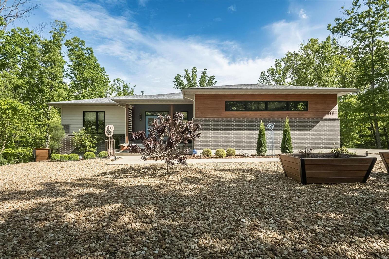 Welcome to your own private country oasis! This unique property sits on 9.16 ACRES surrounded by picturesque scenery and a fully stocked pond. Close proximity to hiking, floating, state parks, and wineries in St. James and Steelville. The contemporary open-concept floor plan offers a kitchen with quartz countertops, 42” custom cabinetry, and peninsula. Living room with modern electric fireplace has large picture window allowing for unobstructed views of private pond with dock. Spacious primary suite features separate tub, zero entry shower and dual walk-in closets. Half bath and laundry room round out the main floor. Lower level with walkout features 3 more bedrooms, full bath, large rec room with wood burning fireplace, and kitchenette- perfect for hosting guests. Outdoor living space offers covered composite deck and spacious patio area with firepit. Oversized 2 car garage and zoned heating and cooling. You will not want to miss this serene retreat! Additional Rooms: Mud Room