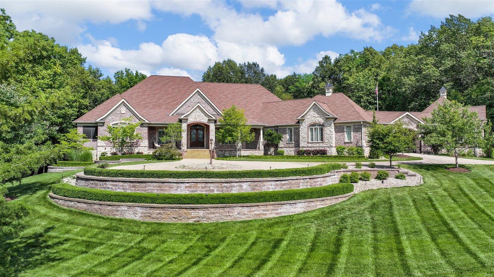 Welcome to THE ULTIMATE DREAM HOME IN OFALLON featuring an elegant circle driveway and gated courtyard with 6-car garage. Home includes over 9000 sq ft of FABULOUS featuring a Grand Entry Foyer, 4 bdrm, 6 baths, Den, formal living rm & hearth rm with fireplaces, custom shelving and vaulted ceilings, formal dining rm, Gourmet Kitchen with top-of-the-line appliances, built in coffee maker, recess lighting, custom cabinets, multiple center islands, wine cooler, ice maker breakfast rm and breakfast bar. The Primary bedroom offers coffered ceilings, walk in closet, built in coffee maker & fridge, fireplace, LUXURY bath with separate tub, 6 head shower & dual vanities. The elevator that takes you to a Magnificent lower level boosting a large great rm with fireplace, multiple bar areas, office which could be additional bedroom, game rm, gym area w/custom gym floor & workshop. The outdoor space offers covered several entertainment areas, 2 fireplaces, kitchen-aid gas grill, pool with hot tub.