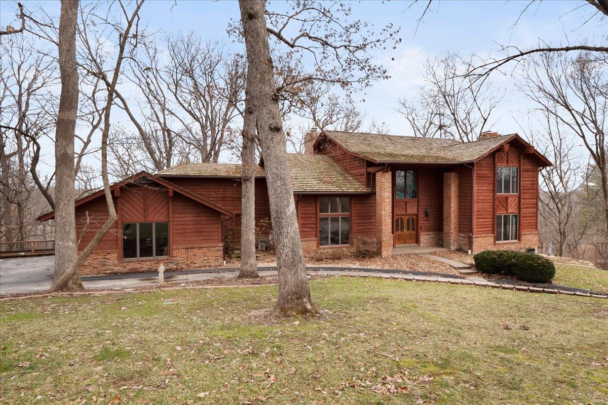 CHARMING 2-story, CUSTOM BUILD home in the desirable Caulks Creek Ridge subdivision resting gracefully on the top of the ridge on 6.5+/- beautiful acres providing AMAZING views & nature surrounding you everywhere. The home boasts 5 Bedrooms, 4 full & 2 half baths, with 6,100+/- sqft. A covered front porch & grand 2-story entry foyer welcomes you. Living room features wood floors & wood burning FP. Eat-in kitchen flaunts custom cabinets, granite/Corian, center island, sliding glass walk-out & brick floor-to-ceiling see-through wood burning FP to great room. Completing main level is a dining room, sitting room, great room, laundry room & 2 half baths. Upper level extends living w/primary suite that features a brick wood burning FP, carpet, walkin closet & bath w/double sink vanity, shower & jet tub. Second bedroom shares full bath. Walk-out lower level boasts a family room, living room, office, 3 additional bedrooms & 2 full baths. Caulks Creek (leads to MO river) runs through property.