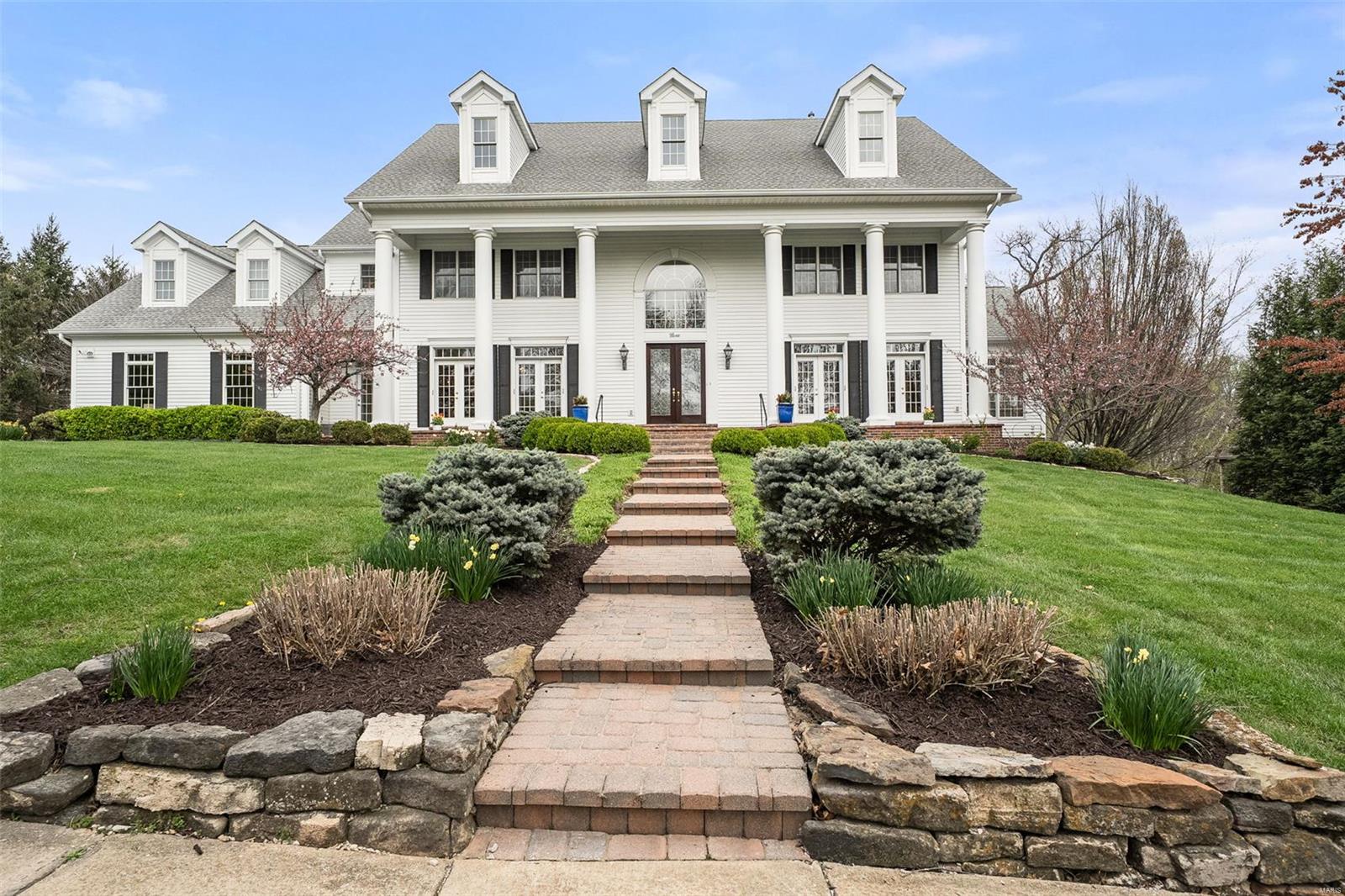 Stately home perfectly situated on 1+ private acres in Ladue School District w/ easy access to the hospitals.  Extremely well maintained newer construction home with fantastic brick front porch.  When you walk inside you'll be greeted w/ a grand sweeping, curved staircase, marble floors w/ diamond insets plus a 2-story ceiling in foyer.  Paneled library w/ built-ins is ideal for a home office, formal DR w/ elegant wallpaper & chandliere, huge great room w/ fireplace and wetbar overlooks private back yard w/ pool, water features PLUS a separate pool house w/ kitchenette & full bathroom.  Sophisticated waiscoting and moldings, large sunroom off great room w/ garden views. Updated kitchen w/ huges island w/ prep sink, gourmet appliances, mud room & rear entry.  Palatial primary suite with spa-like bath, 3 add'l bdrms & bath.  Gigantic finished lower level w/ wet bar, multiple entertaining areas, add'l bdrm & bath + walk out to pool area & ample storage. 3 car garage + dbl. width driveway.