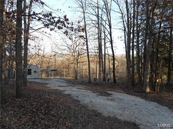 A HUNTERS PARADISE with NO RESTRICTIONS! You will love this wooded wonderland that boasts 13.3 acres nestled at the end of a cul-de-sac. The property has a natural pinch point & a wet weather creek that deer & turkey travel through frequently. The lot is mostly wooded with a nice open space that is a park like setting. You will have plenty of room for a huge vegetable garden. This is a perfect spot to build your dream home (well & septic set up for a 4 bedroom house). There is currently a 2 bedroom, 2 bath, 1056 sq ft, 16x66 mobile home. The home offers: newer laminate flooring, open floor plan, all electric, smooth top stove, ceiling fans, built in bookshelves, & a large master bedroom w/ private bath. There is a 25x25 shed for extra storage. Home sits approximately 4 miles outside of Hawk Point & just 1/4 mile off of the paved Hwy. Low taxes and Troy R-3 Schools. - Cash or Conventional financing, no FHA or USDA.