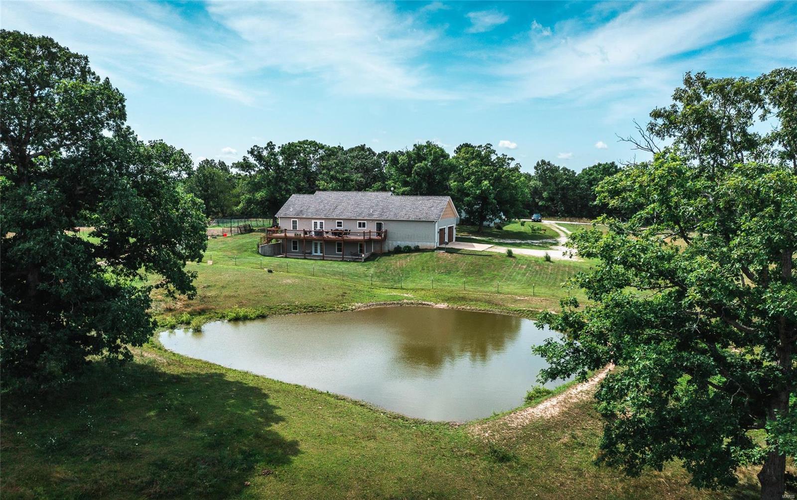 Gorgeous home with a beautiful setting sitting on 20 acres just about 10 minutes outside city limits.  Quiet and filled with pretty views, this property is perfect for your mini farm.  The home has 4 bedrooms and 2 baths with the master suite being on the main level along with the laundry room/mudroom, which is right off the 2 car attached garage.  Right off the dining area is your access to the back deck that spans the length of the home and has the most stunning views on the property.  Downstairs in the walk-out, partially finished basement is the 4th bedroom and another living area.  It has ample storage and a roughed-in, framed up room for a bathroom.  Outside the land is fenced and cross fenced, has 3 ponds, a barn, and a 24x30 workshop.  It is ready for your animals, whatever they may be!  This property will not last long, schedule your showing today!