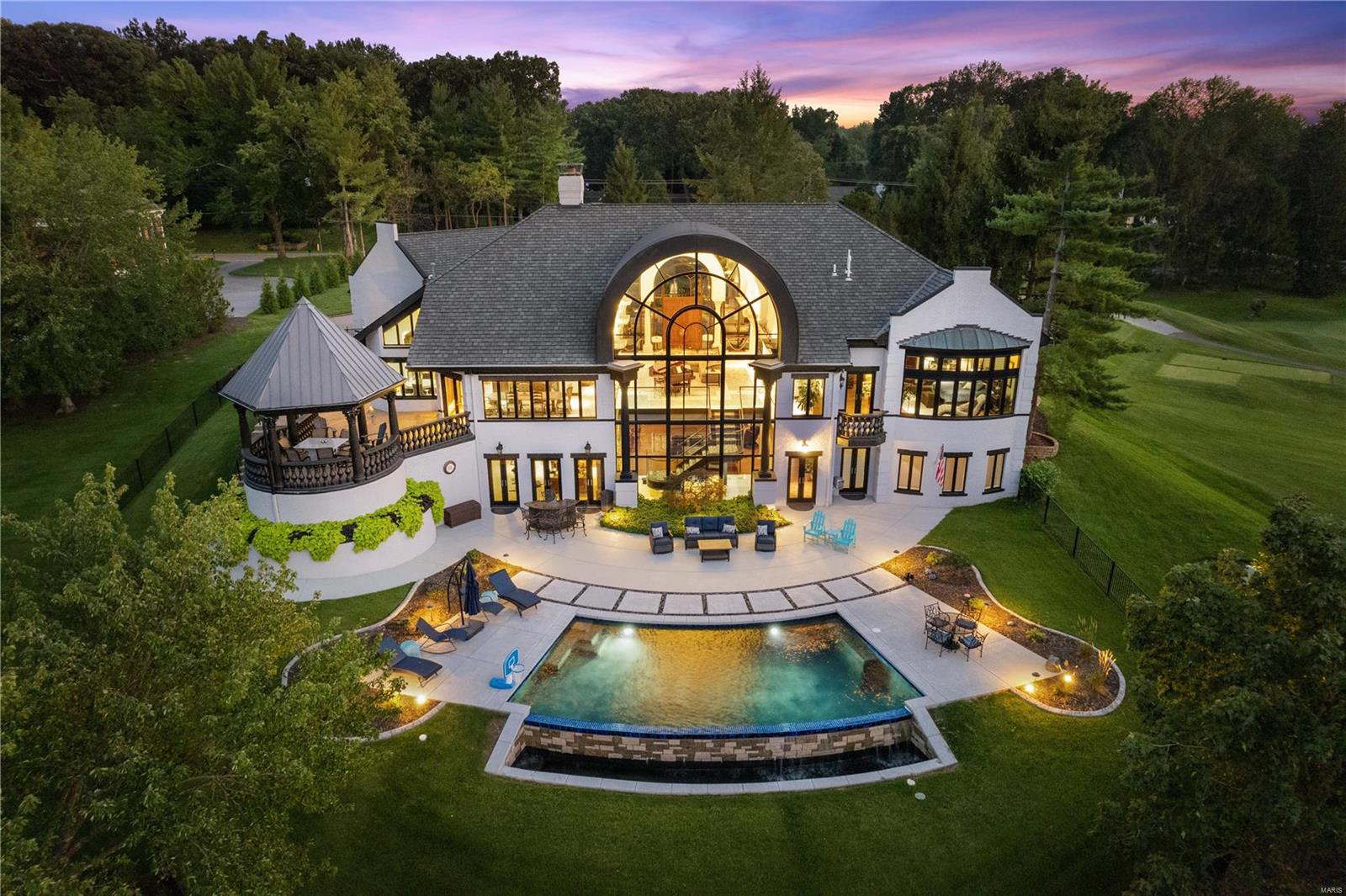 It's all about the lifestyle...Discover the epitome of resort-style living in this exquisite home! Greenery surround circular drive & stunning fountain welcome you. Stepping into the great room unfolds a breathtaking display of towering wall-to-ceiling windows, framing panoramic scenery of the golf course. Floors are gleaming marble surfaces, complemented by meticulous artisan millwork. Main floor master suite is accompanied by custom dual closets, a lavish bathroom & abundance of storage solutions. Kitchen stands equipped with state-of-the-art appliances, inviting island for seating, adjacent eat-in area, a cozy hearth room, & built-in office space that harmoniously integrates function and style.  The lower level is home to three additional bedrooms, accompanied by two full baths and recreational room providing ample space for leisure and entertainment. This level extends to the outdoors where you find a pristine infinity-edge pool, an inviting patio, a charming gazebo, and BBQ grill.