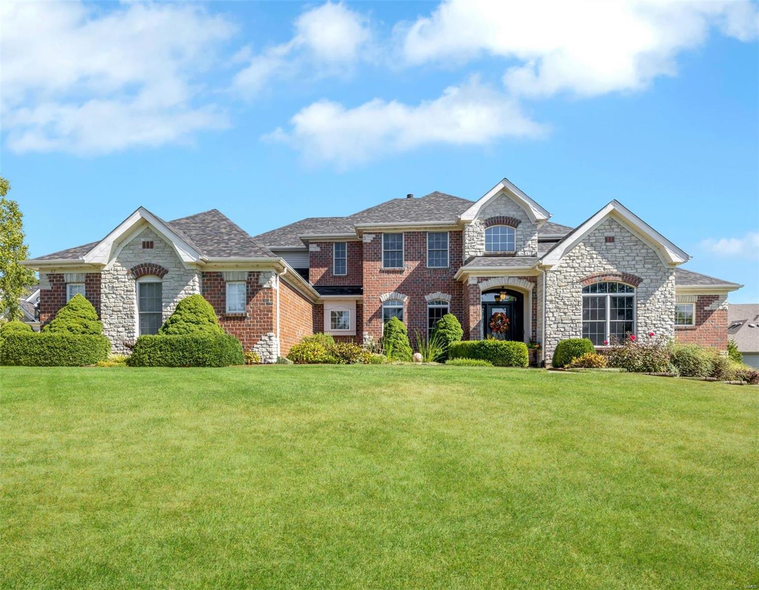 Discover this charming 1.5-story home, offers over 4300 sqft of finished living space on a picturesque 0.72-acre lot with a brick & stone exterior. Main floor features a primary suite w/ 2 walk-in closets & a luxurious bath. Stair lift to upstairs, 3 spacious bedrooms each have walk-in closets, with one having a private bath & the other two sharing a Jack and Jill bath. Home's elegant design includes travertine tile throughout the grand 2-story foyer, kitchen, breakfast area, & hearth room. Sunlit hearth room is a cozy retreat with wood-burning fireplace. Kitchen boasts stainless steel appliances, quartz countertops, & a walk-in pantry. 2-story living room showcases a marble gas fireplace. Finished lower level adds a 5th bedroom, full bath, rec room, wet bar & ample storage. Additional features include a new roof, updated A/C units, 2 water heaters & a water softener. Covered deck great for entertaining. Garage is heated, insulated & has gladiator storage system!!