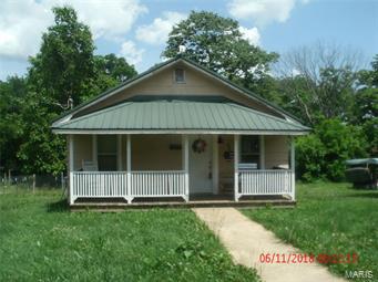 2 Bedroom Cottage with some updates.  Has Metal Roof, wall was removed between Living Room & Dining area so it is all one big room.  Kitchen is long and narrow with a bathroom at one end and laundry area at the other end.  Bathroom has some updates.  Original hardwood floors but could use some work.  Nice covered front porch.