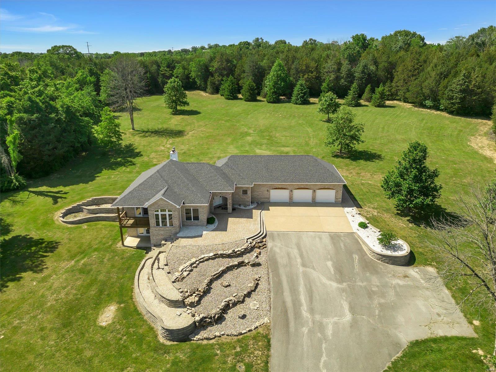 Welcome to this peaceful country living home surrounded by 13 stunning wooded acres, which is situated at the end of a private drive. This beautiful ranch home offers a 2100 sq ft main floor with 3 bedroom, 3 full baths. This home has been meticulously maintained and backs to woods with beautiful scenery. Fall nights can be spent in front of the wood-burning fireplace while enjoying the view of this park-like acreage. This home also features a large, open kitchen with a Jenn Aire range that includes a grill and griddle.  You will find a large master suite with full bath and spacious walk in closet. Two additional full guest bathrooms and two bedrooms with large main floor laundry, three car garage, and spotless basement waiting to be finished off with a full bath rough in already existing.