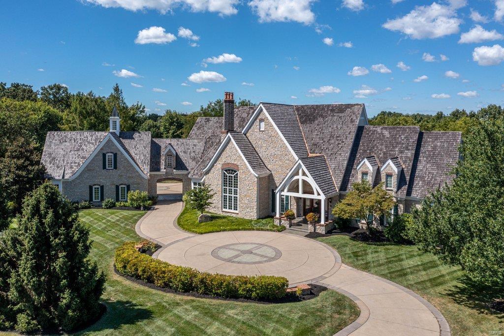 Exquisite European-inspired Estate home from award-winning Johnson Development. Grand marble entry foyer leads to private study with stone fireplace & custom built-ins, elegant dining room with atrium door to terrace & stunning great room with cathedral ceiling, floor-to-ceiling stone fireplace flanked by built-in bookcases & dramatic palladian window. Exceptionally large kitchen with 42” glazed cabinetry, granite countertops, commercial grade appliances & butler's pantry adjoins breakfast room with French doors that open to patio. Coffered master bedroom suite features wide bay window & beautifully appointed bath with jetted tub. 3 Additional ensuite bedrooms complete the main floor living quarters. Lower Level entertainment space includes recreation room, media room with granite fireplace, gathering bar, office, workout room & guest suite. Situated on parklike 3.6-acre grounds with hot tub & stamped concrete terrace surrounded by landscaped gardens plus porte-cochere & 6-car garage.