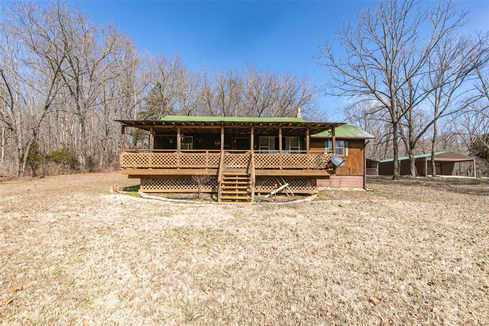 If you are looking for a secluded area to hunt, this is your honey hole! This 2 bedroom, 1 bath, wood sided, hunting cabin is nestled in the backwoods of Carter County, Missouri. The cabin comes furnished with 2 sets of bunk beds, 1 additional twin bed (mattresses and bedding included), sofa, recliner, dinette set, refrigerator, gas stove/oven and microwave. Enjoy a beautiful view overlooking the valley on the covered front porch or kick back and relax on the covered back porch, whichever one you choose will be relaxing. Property also has a 384 sq ft barn with a loft area and 2 11x24 lean to and a large metal shop building with a wood stove. Also included are 2 riding mowers and a zero turn mower. The entire property is fenced and also includes a fenced in garden area. All of this priced at $139,900!