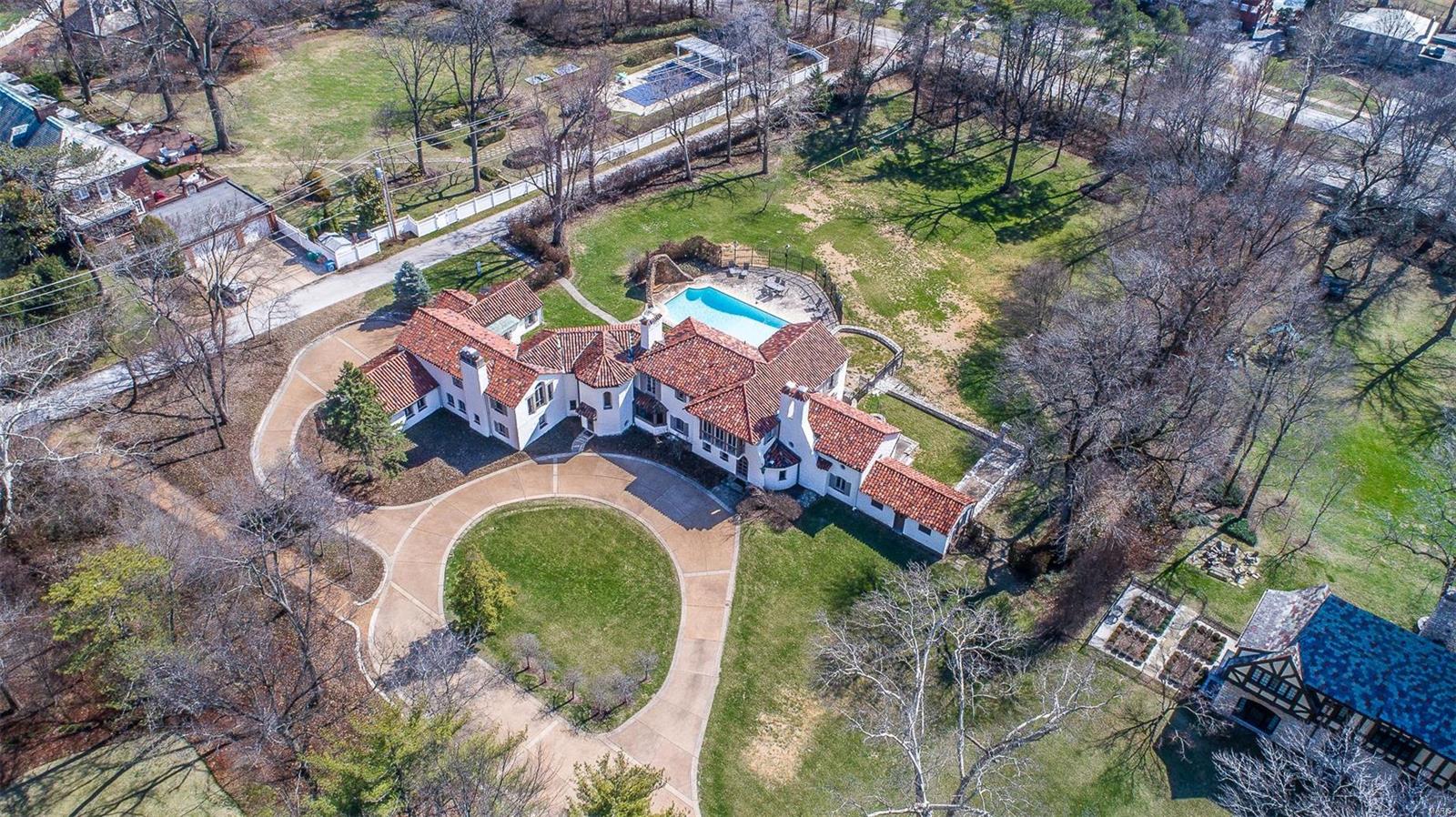 A picturesque example of a Maritz & Young home designed in the Spanish Colonial style w/ nearly 2 acres in Clayton’s Brentmoor Park. Originally built in 1924, an addition nearly doubled the size of the house in 1935. White stucco walls and a red tile roof, scalloped lintels & corner octagonal tower greatly define the home’s character. Updated by the current owners with geothermal system, newer kitchen and bathrooms, & renovated coach house while keeping in the tradition of the leading residential architectural team of that generation. Enjoy your summer evenings on the terrace overlooking the salt water pool w/ historic grotto.  Placed at the end of a cul-de-sac privacy is guaranteed. A grand house for entertaining with circular drive.  Formal entertaining areas are balanced with an informal family room and master suite retreat. 4-car garage. Become an important part of St. Louis’ history as a caretaker of one of Clayton’s most architecturally significant residences. 3D Tour available.