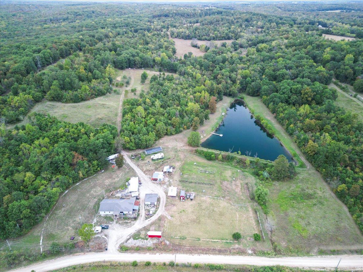 Looking to retire or move your extended family to your own recreational working farm, then look no further. Welcome to Hilltop Farm, This 40 acre m/l property is set up and ready for your family and your livestock. There is an 1.5 acre springfed lake on the property fully stocked with a dock and ready for family fishing. The 5 bedroom 3 bath home, though built in 1970 has had many updates including new windows, new kitchen cabinets and appliances. Outside you will find several orchards with producing apple, pear, peach trees, as well as a working greenhouse, grape arbor and new trees for the future. The owners have hunted and tagged several large whitetail deer and turkey right on their own property. Also, included is a working walk in cooler for your meat, fruits and vegetables, and under the house a canning cellar both of which could be used as a storm shelter. Lastly, there is another building sight equipped with another well, septic & electric already in place .Minutes to Stockton
