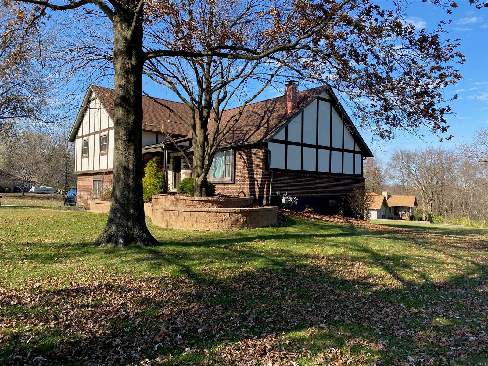 Welcome to this one-owner, custom-built home on over one acre in the heart of St. Charles within walking distance to the Katy Trail. Upon entering this English Tudor multi-level home, you will discover the unique floor plan, perfect for both entertaining and working from home. Experience the quiet neighborhood with expansive lawns and bluff views. Four bedrooms including a master suite on the upper level with updated baths. The main floor with a spacious living room and wood-burning fireplace opens into a formal dining room, adjacent to the eat-in kitchen with sparkling solid surface countertops. A lower level fireplace adorns the family/addition room with a half bath. Through the garage you will find the walkout sub-level basement which could easily be turned into a media room or great space for the kid that just won't move out - you won't even know they are there. Enjoy the serenity of the no maintenance, composite deck located off the lower level family room.Seller is licensed agent