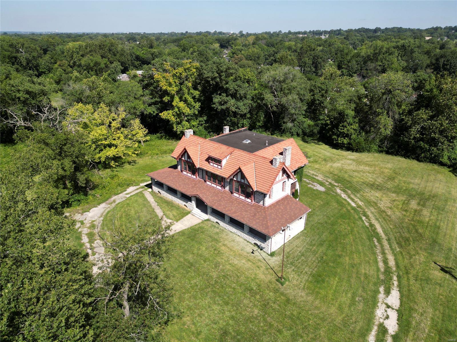 PREVIOUS PRICE WAS STARTING BID FOR 09/11 AUCTION. Home is being Sold As-Is. Built in 1905, the craftsmanship of this estate reflects the timeless architecture of Barnett, Haynes & Barnett. Situated on 9.85 acres this AWESOME 6966sf structure made from hand cut MO limestone exhibits a beautiful tile roof & boasts a timeless presence! Wraparound porch has been updated, as well as the windows...98 of them! Newer 400amp service & newer main water line. Complete list of improvements is attached. Estate backs to a creek bed, an area for pond/lake. Bring your IMAGINATION & LETS GO!! Property is currently zoned Res, but could be rezoned commercial. Had been approved thru MH for multi-use previously, see attached conditional approval. Turn this home into the Estate of your dreams or consider developing the land for community style living? The choice is yours!