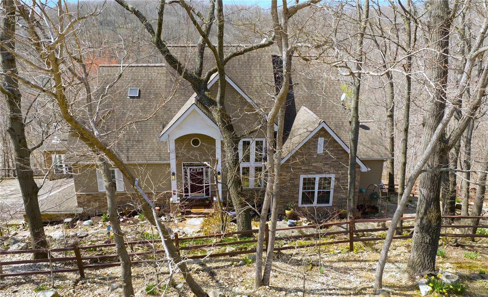 1.5 story home on secluded 4 1/2 acres in highly desired LaSalle Woods located in Wildwood.  Serene woodsy setting, lovely flagstone walk ways & landscaped property is a cozy hillside retreat.  2 story foyer opens to great rm w/cathedral ceiling & floor to ceiling stone FP & wall of floor to ceiling windows overlook peaceful private view.  Spacious kitchen/breakfast rm offers center island, SS appliances, new electric cooktop & large breakfast bar, walk-in pantry, desk.  Off kitchen-sunroom w/wood stove , screened porch & nice sz laundry rm.  ML Master Bd has loft & private deck looks out to stunning scenery & inground pool & has luxury bath w/heated floors, custom walk-in closet.  Bed 2 & Full Bath on ML.  UL- office & 3rd Bed w/private composite deck.  W/O LL - media rm w/stone, liv rm w/2nd stone FP, 4th bed w/triple closets, bonus rm, 3rd full bath, storage.  2 car oversz garage & mudroom.  Gorgeous inground pool & level fenced area w/playhouse.  Chicken coop & stone firepit too! Additional Rooms: Sun Room