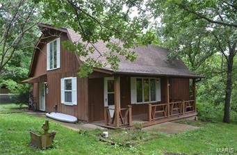A little piece of heaven in the woods.  Neat and unique 2 bedroom, 2 bath home awaits you at the end of a circular drive backing up to woods.  Main floor includes remodeled kitchen with all stainless steel appliances, tile floors that flow from dining area though to kitchen.  There is a pantry, guest bedroom or office, a bath with shower and storage space.  The living room has a featured stone fireplace, barn wood wall and impressive stone half way up the walls.  Some furniture will stay.  Upstairs is the master bedroom with step out balcony, walk in closet, skylights, a jetted tub, and convenient washer dryer tucked in the bathroom.  Since 2016 Owner has added new electric panel, PEX plumbing, flooring in the living room, a high efficiency Pellet/Corn wood burning stove, and fencing.  Close to an arm of the Mark Twain Lake.  Make your appointment.