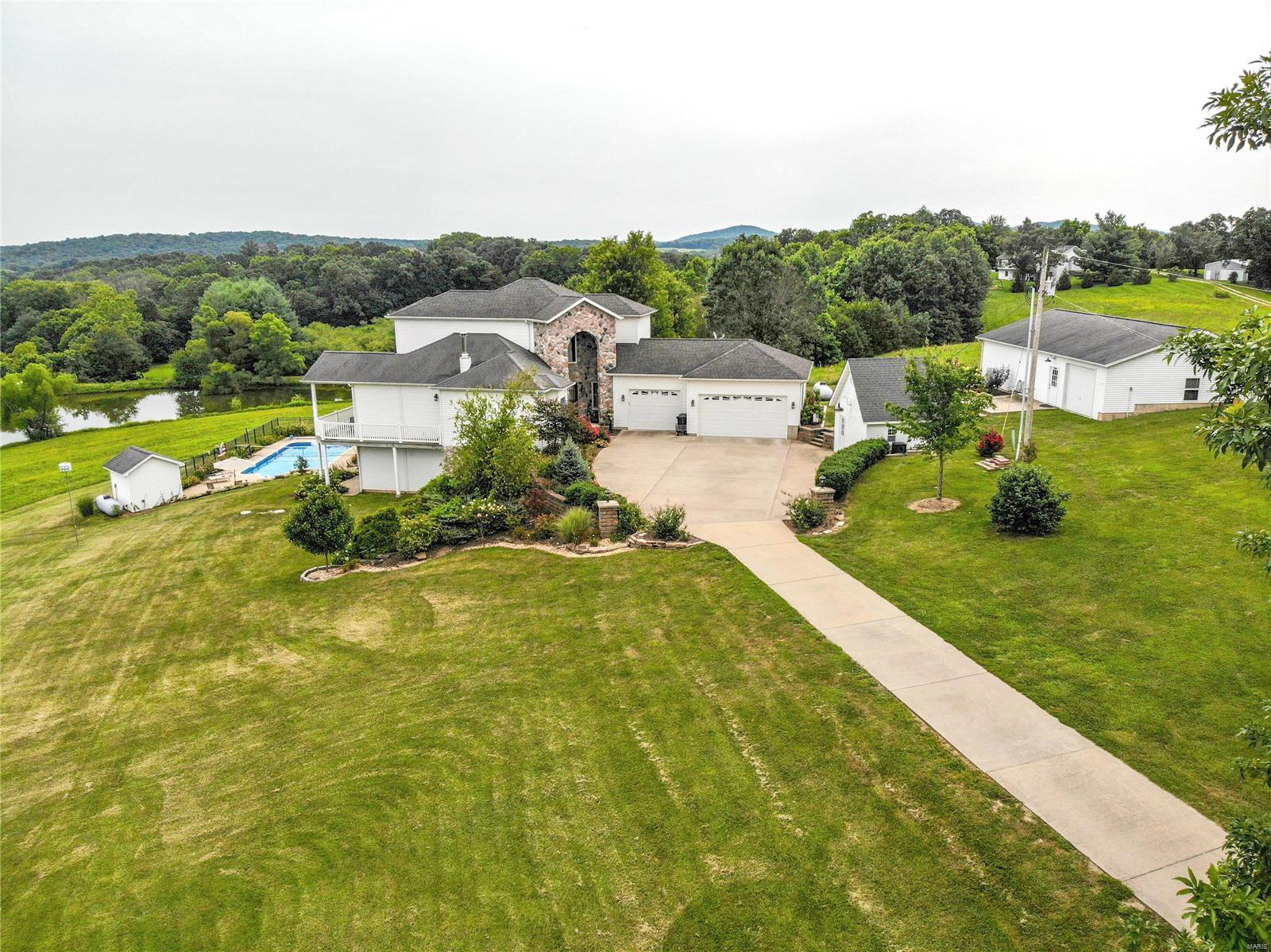 Architectural dream. Custom, 4,000+sq ft 2-story, on 5+ acres. Hardwood floors throughout, whole house surround sound, inground pool, lake access, huge 3-car garage. Exceptional, heated 44x30 workshop/garage. Windows & glass doors offering panoramic views. Separate dining & renovated kitchen; custom cabinets w/leaded glass, quartz countertops, flush mounted sink, center island, 2 pantries, gorgeous fixtures, stainless-steel appliances & unique breakfast room turret. Upper level offers a private master suite w/balcony, bay windows, room sized walk-in closet & luxurious bath w/oversized soaking tub. Living room w/ wood-burning stove, stone surround & mantle. Main floor bedroom w/access to covered wrap around composite deck, bath w/step-in shower. Stunning spiral staircase from 2nd floor to lower-level w/large family room, 3rd bedroom, 3rd full bath, 2nd unique dining area turret w/walk out to fabulous paver patio. Beautiful landscaping & garden area, plus shed & other outbuildings.
