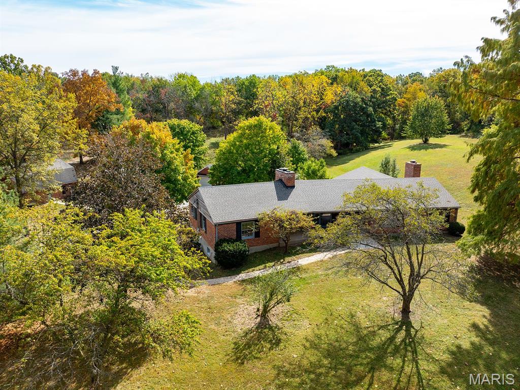 Almost unbelievable! A hidden gem with surveyed 13.387 acres within the city of Hannibal! Included is the approx. 2600 sq. ft. brick raised ranch style home, a 35'x25' outbuilding, a 2-car tuck under garage plus a 1-car detached garage, & peaceful "country" tranquility... in town! The old barn previously was home to a couple of horses. Here's a few other details: Quality steel beam construction! 3 spacious bedrooms & 2 full baths. Beautiful crown molding, radiant heated floors, massive closet space including an entire row of closets along hallway, & 2 fireplaces that add to the ambience. Expansive covered porch is access to the beautiful front entry foyer that extends through the home to the back patio. This private patio & the massive living room w/wall of windows both offer wonderful views of the wooded acres sheltering deer as they romp & play.  If desired, Buyer could add a driveway to front entrance for any guests that need to avoid steps! (Occasionally, Seller has driven to the front as if a circular driveway existed.) The outbuilding with loft for storage offers the perfect place to enjoy your hobbies, park more vehicles, and/or store your grown-up style toys!  Walking bridge leads to Gazebo for a different place to relax. This one-owner home was built by well-known and respected contractor, Wallace Smashey, who lovingly built this home for his family.  Now it is available to be YOUR oasis and forever home!