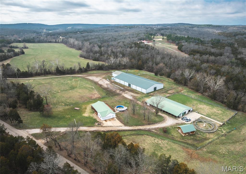 Turnkey equine estate located along scenic Cabanne Course Creek featuring professional-grade facilities, a beautifully maintained ranch-style home, and outstanding income-producing potential. Conveniently located just over an hour from St. Louis and approximately 20 minutes from Park Hills, this property offers a rare combination of privacy, accessibility, and established equestrian infrastructure. The residence offers approximately 3,640 m/l square feet with 3–4 bedrooms, multiple baths, and a warm rustic feel throughout. Hardwood floors, updated finishes, vaulted ceilings, a cozy fireplace, and two spacious living areas create a comfortable setting for both everyday living and hosting guests. A walkout basement and dedicated mud/laundry room add convenience for an active ranch lifestyle. Designed with versatility in mind, this property is exceptionally well suited for a variety of equine and event-based business opportunities. The impressive 200' x 100' red-iron indoor arena/event center features lighting, a sound system, concession area, and restrooms with showers, making it ideal for year-round barrel races, team ropings, rodeos, horse shows, clinics, riding lessons, auctions, and special events. A 210' x 100' lighted outdoor arena provides additional space for competitions, training, and large-scale gatherings. Supporting facilities include a 120' x 60' metal barn with 18 horse stalls, wash bays, tack rooms, and ample storage, creating an excellent setup for horse boarding, training programs, breeding operations, lesson programs, or a full-service equestrian business. A 4-horse hot walker further enhances the property's appeal for serious horse owners and trainers. The well-maintained pipe fencing, cross-fenced pastures, and automatic waterers provide efficient livestock and pasture management while offering ample turnout space for horses. A pavilion and fire pit create a welcoming atmosphere for competitors, spectators, and guests during events. Whether your vision is a premier barrel racing facility, rodeo venue, horse boarding operation, training center, event destination, or private equestrian retreat, this property offers the infrastructure and location to support a wide range of opportunities. Facilities of this caliber are increasingly difficult to find, and the replacement cost of the arenas, barn, fencing, and supporting improvements would be substantial.