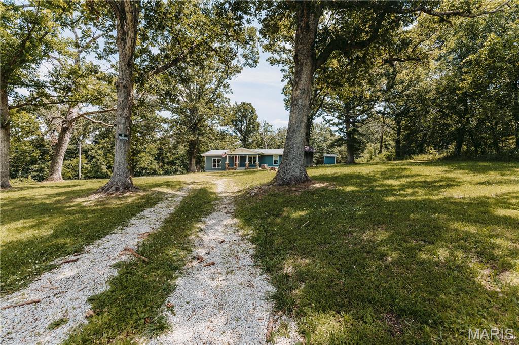 Updated 3-bedroom, 1-bath home situated on just over an acre outside the city limits with convenient access to Fort Leonard Wood, Rolla, and I-44. Set back from the highway, this property offers mature trees, attractive curb appeal, and a welcoming front entry. Inside, you'll find fresh paint and recent updates, with finishing touches being completed. The kitchen opens to an oversized family room featuring French doors that lead to the back patio, creating a functional layout for everyday living. The bedrooms are located on the opposite side of the home from the main living area, offering separation of space. The laundry room provides direct access to the backyard, and the full bathroom is centrally located. Outside, the circular driveway offers ample parking, while the spacious lot provides room for outdoor activities, gardening, or future improvements. Enjoy the privacy of a wooded backdrop with the convenience of nearby shopping, schools, and major highways.
