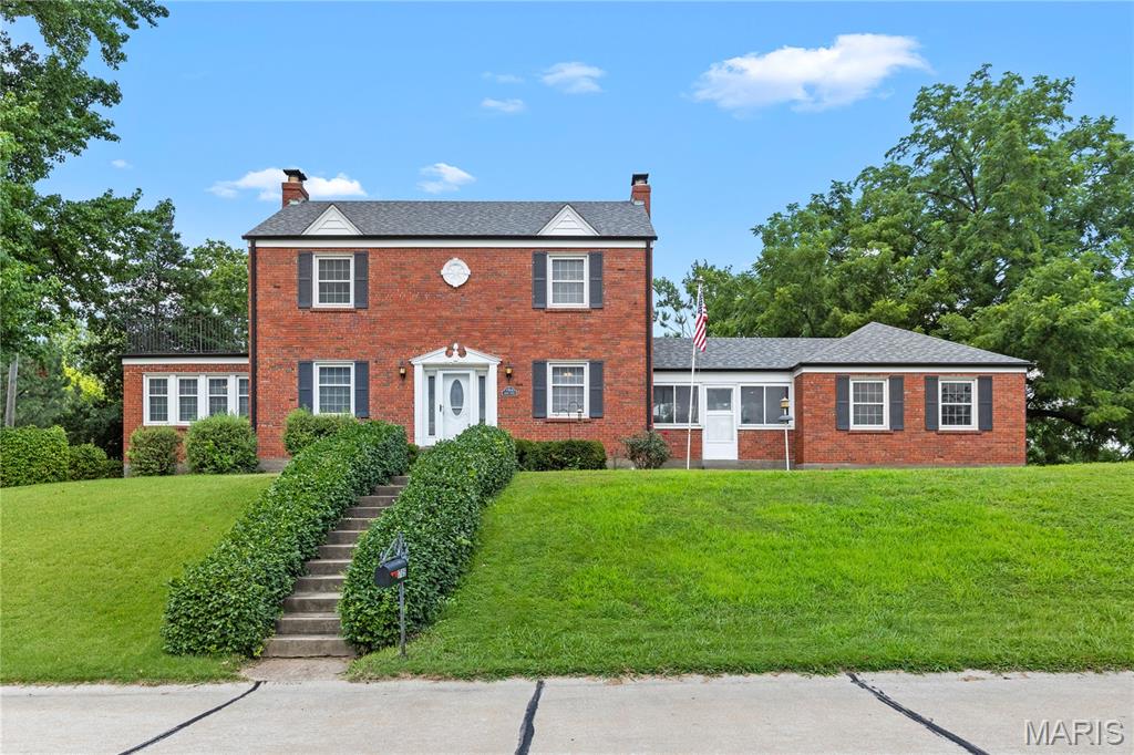 This traditional 1939 two-story home balances historical character with functional, modern living. All brick 2 story home in Hazelwood offers 4 bedrooms, 2 1/2 baths. On the main level is a large living room with a wood burning fireplace, formal dining room and a sunroom off the family room. The breezeway/bonus room between the garage and the kitchen is a full sized room that has it's own fireplace and can be used in many ways. Up the beautiful staircase you find 4 bedrooms and updated bathroom. There's even a balcony you can step out onto & enjoy the fresh air from one of the bedrooma s The lower level is partially finished offering a recreation room & full bath. It also offers amazing storage. With your own 1/2 acre lot & inground pool you can enjoy the outdoors in so many ways and enjoy the privacy of your own personal park like yard.  You can also walk just down the street to walking trails, a fishing pond and pavilions in Truman Park. With mature trees & this beautiful lot you can have your own private oasis & yet be just minutes from the highway.