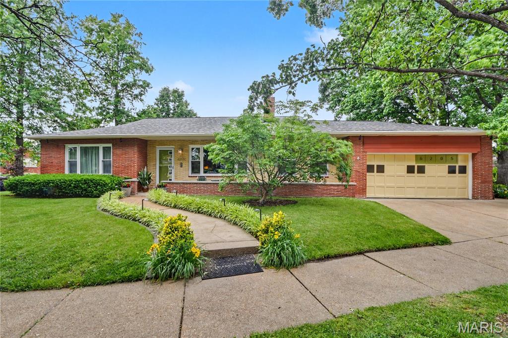 Situated on a sweeping corner lot, you’ll fall in love with this charming midcentury ranch in the highly desirable St. Louis Hills Estates neighborhood. Filled with natural light from large windows and featuring warm wood floors throughout, this home offers the perfect blend of midcentury modern character and updated functionality. The open floor plan is ideal for entertaining. This home features three main-floor bedrooms, a spacious living room with a gas fireplace, a family room, a dining room, a sunroom, and a convenient main-floor laundry area. The finished lower level expands the living space with a second kitchen, a second oversized full bathroom with a walk-in shower, a cozy family room with a gas fireplace, bar area, two bonus rooms, a workshop, and abundant storage. Impeccably maintained with attention to original design detail throughout. A new roof was installed in 2025.
Step outside to enjoy the lushly landscaped side garden and the raised deck overlooking the backyard — perfect for outdoor seating and alfresco dining. The attached two-car garage with Vevor interlocking, modular garage floor tiles provides convenience and direct access to the kitchen, making unloading groceries and daily errands effortless.
Located just a short walk from Francis and Willmore parks and close to shopping and dining, this is a wonderful opportunity to own a truly special home in one of St. Louis’ most sought-after neighborhoods.