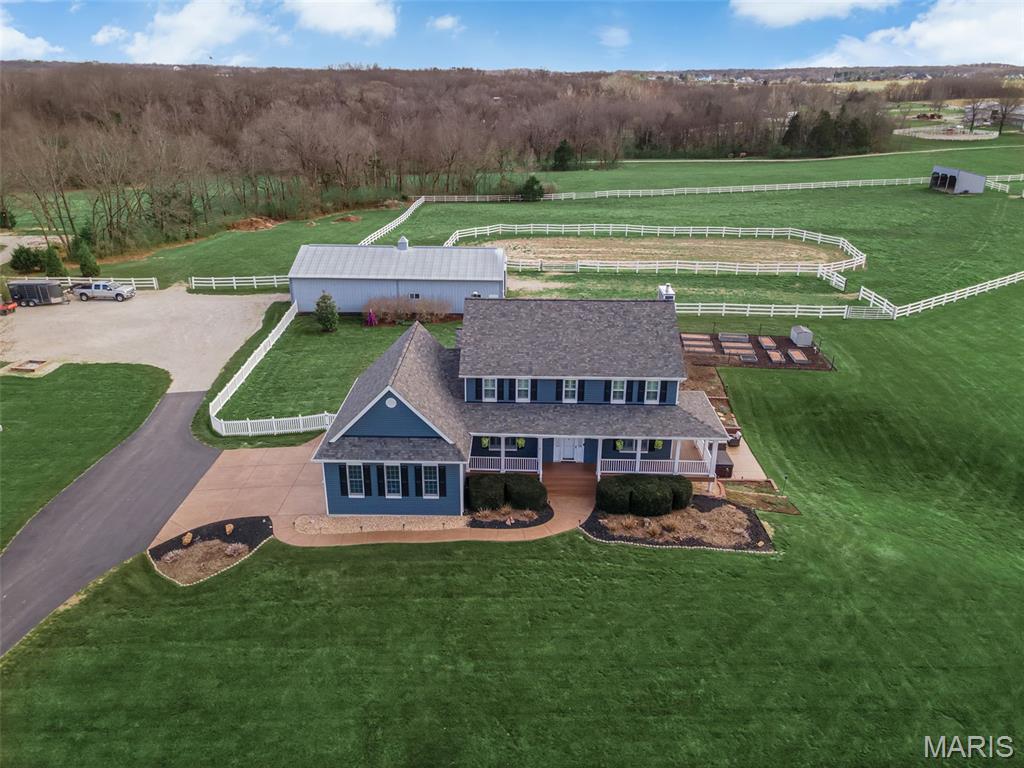 Double Mustang Ranch — a 15-acre equestrian estate set among rolling hills and surrounding horse properties, where refined living meets a fully developed, turnkey equestrian setup designed for both lifestyle and function.

Set behind a long private drive and framed by classic white equestrian fencing, the property delivers the setting buyers seek but rarely find. Just minutes from Broemmelsiek Park with miles of riding trails, this location supports both daily riding and extended trail access. A 70x35 barn built for function and longevity features four stalls, tack room, horse wash area, hay storage, electric, water, and lean-to for additional coverage. Surrounding the improvements, a defined riding arena, run-in shelter, and multiple fenced paddocks create a well-planned equestrian environment, with additional open acreage available for rotation, expansion, or future use.

The home offers over 3,800 square feet with a layout that feels intentional and elevated. The high-end kitchen serves as the centerpiece with expansive workspace, custom finishes, and seamless flow into the great room—ideal for entertaining. Natural light defines the main spaces, while a dedicated office and formal dining room add refinement. Main floor laundry and an oversized 24x35 three-car garage add everyday convenience, while the four-season room and covered patio extend the living experience outdoors year-round.

Upstairs, the primary suite offers privacy and scale, with a well-appointed bath and custom closet, featuring a spacious layout and elevated finishes that deliver a true spa-like experience. Additional generously sized bedrooms provide comfort for family or guests.

The walk-out lower level features a private in-law suite with a second kitchen and full bath, ideal for multi-generational living or extended stays, along with a large recreation area and additional sleeping or office space. Outdoor features include established garden areas and a sitting area perfectly positioned to take in sunset views across the property.
