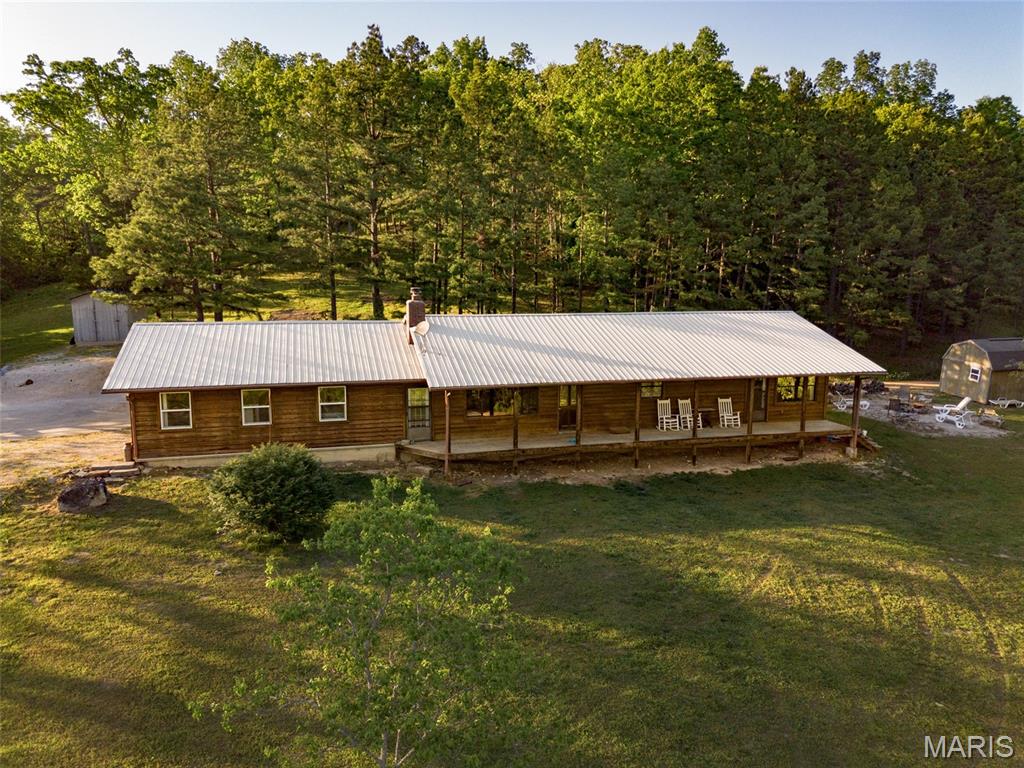 Welcome to the country, where quiet mornings and wide-open skies set the tone for everyday living. This charming 3-bedroom, 1-bath cedar-sided home rests on 6.78 picturesque acres, surrounded by gently rolling land and the soothing sounds of nature. Located just minutes from Bunker, it offers the perfect balance—close enough for convenience, yet far enough to feel like your own private retreat. Start your day on the expansive front porch, coffee in hand, as deer wander gracefully through the yard and wild turkeys pass by in the distance. Inside, the home welcomes you with an open floor plan that creates a warm, inviting flow between the spacious living room and kitchen—ideal for gatherings, laughter, and making memories. On crisp autumn evenings, the large wood-burning fireplace becomes the heart of the home, filling the space with a cozy glow and the comforting crackle of burning logs. The three bedrooms provide flexibility for family, guests, or a home office, while the oversized master bedroom stands out with its generous proportions and potential to add a private ensuite bath tailored to your vision. The bathroom offers ample space and storage, blending practicality with comfort. Every corner of this home reflects a slower, more peaceful pace of life—where nature, space, and simplicity come together beautifully.