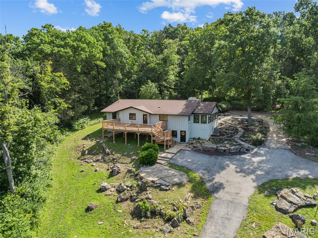 A slice of paradise IN THE WOODS! OVER 4000 sq ft of total living space. 7.4 acres of beautiful countryside that's less than 10 MINUTES from TOWN! This 3 bedroom, 3 bath home offers a perfect blend of modern comfort and rural charm. The open floor plan is highlighted with vaulted ceilings and accented with wood beams and windows abound. The updated wood floors run throughout most of the home. The Great Room is spacious while also providing a cozy charm with the wood burning FP. The charm continues into the The kitchen, the heart of this property. The kitchen not only has updated quartz countertops, floating shelves, plenty of cabinet space, backsplash, stainless steel appliances, but it has a luxe and spacious island that steals the show. The primary suite is on the main floor along with the laundry/mud room and two additional spacious bedrooms. Natural light is showcased throughout the inside of the home and continues into the back. Morning coffees and evening sunsets can be enjoyed while listening to the rustling creek from the comfort of the brand-new deck that overlooks the nature surrounding this home. The Lower Level starts with an additional generous living space complete with built-in bookshelves around the FP, kitchenette, a walk-out, sleeping area, full and modern updated bathroom, and more. Whether you're entertaining, homesteading, or simply want your own oasis , this stunning property is waiting for you.
