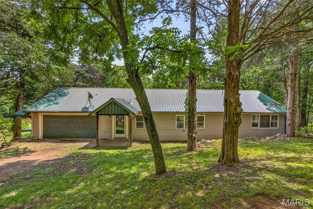Enjoy peaceful Saint Francois River frontage in this beautiful, raised ranch home surrounded by a picturesque park-like setting. Designed to capture the river views, the home features a covered front porch and glassed-in sunroom perfect for morning coffee or evening relaxation. The spacious great room offers soaring open beam ceilings, an open-concept kitchen/living/dining layout, and a cozy wood-burning stove that creates the perfect gathering space. The main level also includes a private primary suite with soaking tub, additional full bath, laundry and utility area, plus a massive 19x19 storage room with concrete ceiling. Upstairs, you'll find another bedroom, full bath, and an oversized family room overlooking the main level below. Additional features include vinyl siding, metal roof, electric furnace and central air, plus a supplemental wood-burning furnace. Outside amenities are exceptional with a 2-car attached garage featuring a loft room above, large metal pole barn/shop building, 30x24 metal-sided shed, and additional storage shed. If you’ve been searching for riverfront living with space, privacy, and endless possibilities — this is it.