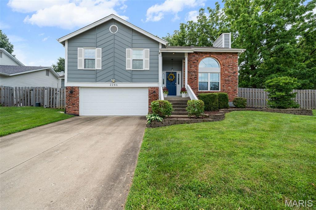 Adorable and move-in ready, this charming home is perfectly situated in a prime St. Charles location, just minutes from the Muegge Road, Highway 364, and Highway 94 interchange, making commuting and everyday errands a breeze. Step into an inviting, open floor plan with vaulted ceilings that create a bright and spacious feel. The living room is filled with natural light and features a cozy gas fireplace, perfect for relaxing evenings. The eat-in kitchen opens through a sliding glass door to a covered deck complete with two ceiling fans, overlooking a fully fenced, private backyard. Garden enthusiasts will appreciate the two raised garden beds, ready for planting. The spacious primary suite offers double closets and a private ensuite bath with a double vanity. The lower level includes a versatile bonus room, ideal for a home office, fitness studio, or craft room. The oversized garage provides ample space for storage, hobbies, or a workshop, making this home as functional as it is inviting.