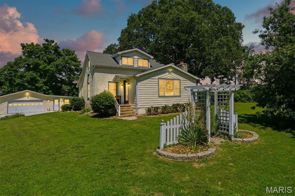 Welcome to your own slice of Missouri country living! Nestled on 10.03 picturesque acres along Pickles Ford Trail in Franklin County, this charming farmhouse-style home offers the perfect blend of timeless character and rural functionality — ready for your hobby farm, mini farm, homestead, or equestrian vision.

Step inside and you'll immediately feel the warmth of a home lovingly maintained and full of character. The main level showcases rich hardwood floors and a show-stopping knotty pine tongue-and-groove ceiling in the living room, complete with recessed lighting that gives the space a warm, cabin-like ambiance. The living area flows naturally into the dining space, making it ideal for gathering after a long day on the land. The classic country kitchen features natural oak cabinetry, electric range, and plenty of prep space — everything you need to cook up a farm-fresh meal. A back door leads directly to a covered porch overlooking the lush, green countryside — your morning coffee spot is already waiting.

This one-and-a-half story home offers comfortable living space across two levels, with the upper level providing additional bedroom space under charming sloped ceilings — perfect flex space for guests, a home office, or a cozy retreat. Additional built-in storage and a full basement round out the home's practical interior, which has been assessed in very good condition. The home also features a masonry fireplace, propane forced-air heat, central air conditioning, and an open porch — all the comforts of home wrapped in country character.

Outside is where this property truly shines. The spacious garage includes a finished addition that makes an ideal flex room — set it up as a home office, workshop, guest room, or hobby space, whatever your rural lifestyle calls for. A covered lean-to attached to the back of the garage adds even more versatility for equipment, storage, or sheltered workspace. Also on the property: a 20x40 steel barn with electric and water, a carport, a storage crib, and a beautifully built 2017 pavilion with concrete patio and stone pillars — perfect for outdoor entertaining. A charming chicken coop connected to a fenced raised bed garden is ready for your flock and your table alike, with two established strawberry beds already in the ground from last season. Charming stone pathways wind through the thoughtfully landscaped grounds, adding to the property's natural appeal.

With over 9 acres of agricultural land — a mix of open ground and mature timber — the possibilities are wide open. Bring your horses, chickens, goats, or garden and start living the rural life you've been dreaming of, all just minutes from the shops and services of St. Clair.

Whether you're envisioning a quiet country retreat, a self-sufficient homestead, or a working hobby farm, 255 Pickles Ford Trail delivers the space, the structures, and the soul to make it happen. Properties like this are rare — schedule your private showing today!