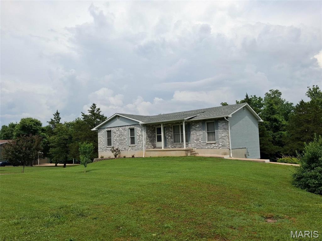 Beautiful gray and white brick home in Desloge, Missouri, located in St. Francois County on nearly two acres of meticulously maintained land with scenic wooded views. This peaceful home features 3 bedrooms, 2 full baths, and an unfinished basement with kitchen cabinets already installed, offering potential for additional living space. This is a pet free home.

The oversized two-car garage provides plenty of room for storage, tools, and hobbies. A long circular driveway accommodates multiple additional vehicles for guests. The driveway literally circles around the entire home. The refrigerator and stove stay with the home. Washer and dryer hook up in basement. Existing washer and dryer do NOT stay with home. Public sewer not available, septic on site.

Enjoy watching deer pass through the lovely wooded backdrop or relax with morning coffee on patriotic bench surrounded by decorative rocks and landscaping. Situated near the end of a quiet cul-de-sac, this home offers privacy while remaining close to city amenities. Located in the North County School District with long-time neighbors and an extremely peaceful setting.

Require use of Special Sales Contract only, selling AS-IS. Inspections can be done at buyer's expense, seller will pay no repairs of any kind and no concessions. Appointment must be made with seller as home is currently occupied.