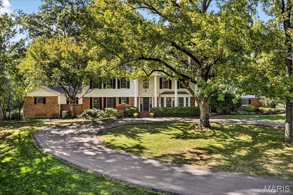 Nestled on a picturesque 2-acre lot in the award-winning Ladue School District, this stately two story, pillared Colonial home exudes timeless elegance and comfort. Surrounded by lush landscaping, mature trees, and a serene, private setting, this residence offers the perfect blend of classic charm and modern convenience.
Step inside to a grand two story foyer with a sweeping staircase that sets the tone for the rest of the home. Featuring 5 generously sized bedrooms and 6 bathrooms, every room is designed to be both spacious and welcoming.
The expansive kitchen and breakfast area offer an abundance of cabinet space, a center island with seating, a built-in desk area, and breathtaking views of the tranquil backyard. Just beyond, an in-ground pool invites relaxation and outdoor enjoyment.
The great room is an entertainer's dream, complete with built-in shelving, a wet bar, a cozy gas fireplace, and access to the private patio and pool area. The first-floor primary suite includes a versatile sitting room (currently used as an office), an en-suite bath with dual sinks and a separate shower and tub, and two large walk-in closets for ample storage.
Upstairs, you'll find four additional bedrooms, with a Jack-and-Jill bathrooms, making it perfect for families or guests. The formal dining room boasts its own gas fireplace and floor-to-ceiling bay windows, while the elegant living room offers a warm and welcoming space. 
The partially finished, walk-out lower level features a recreation area, a cozy family room, a full bathroom, a wet bar, and generous storage throughout.
The laundry/mudroom and a full bath are conveniently located just off the 3-car garage, located down the hall from the kitchen. 
With its beautifully landscaped grounds, inviting in-ground pool, and versatile interior layout, this remarkable home offers privacy, comfort, and convenience in one of the area's most sought-after central locations.
