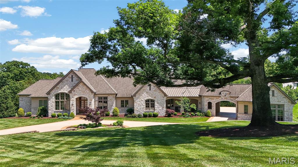 Tucked away at the end of a winding drive and surrounded by 12.58 breathtaking acres backing to Love Park, 262 Dietrich Road is a once-in-a-generation estate where exceptional craftsmanship, timeless architecture, and unparalleled privacy come together to create something truly extraordinary. Offering over 7,000 square feet of finished living space, five private bedroom suites, eight bathrooms, garage space for up to ten vehicles, and resort-style amenities rarely found in St. Louis County, this remarkable property was designed and built without compromise. From the moment you arrive, the home's commanding presence is unmistakable. A limestone and Hardie exterior, Grand Manor roof, custom doors, manicured grounds, and mature trees create a stunning first impression, while the surrounding acreage provides a level of seclusion and tranquility that is increasingly impossible to find. Inside, soaring cathedral ceilings, dramatic beam details, arched openings, rich hardwood flooring, travertine tile, custom millwork, and walls of Marvin windows fill the home with warmth, natural light, and timeless elegance. At the heart of the home, the chef's kitchen showcases handcrafted Mouser cabinetry, an impressive 11.5-foot granite island, Sub-Zero refrigeration, Wolf cooking appliances, Bosch dishwasher, Hoshizaki ice maker, walk-in pantry, and a stunning hearth room anchored by a floor-to-ceiling stone fireplace. The thoughtfully designed floor plan balances grand-scale entertaining with comfortable everyday living, offering multiple gathering spaces, a custom office, built-ins throughout, and two luxurious ensuite bedrooms on the main level. The primary suite serves as a private retreat featuring its own fireplace, boutique style custom closet with island storage, heated bathroom floors, dual vanities, dressing area, air tub, and spa-inspired shower with rain head, body sprays, and premium fixtures. The walkout lower level was built for entertaining and recreation, offering additional ensuite bedrooms, expansive gathering areas, a custom wet bar, commercial-grade fitness center, safe room, and more than 1,100 square feet of storage space. Step outside and discover what truly sets this estate apart. A heated freeform pool with travertine decking, tanning ledge, built-in benches, and lush landscaping creates a private resort atmosphere. Just beyond, an incredible octagonal pavilion serves as the ultimate outdoor entertaining destination, complete with a wood-burning fireplace, outdoor bar, built-in Wolf grill, Sub-Zero refrigeration, and full bath. Whether hosting unforgettable celebrations, enjoying summer evenings by the fire, or simply taking in the beauty of the surrounding acreage, every inch of this property was designed to bring people together. Built to an exceptional standard with 12-inch poured concrete foundation walls, 600-amp electrical service, generator readiness, dual 80-gallon high-recovery water heaters, three-zone HVAC, central vacuum, and countless custom upgrades throughout, this is a home that reflects a level of quality rarely seen today. Adding even more value and future potential, the offering includes an additional 1.32-acre parcel with Dietrich Road frontage. More than a luxury home, 262 Dietrich Road is a private legacy estate - a place where generations gather, memories are made, and dreams become reality.